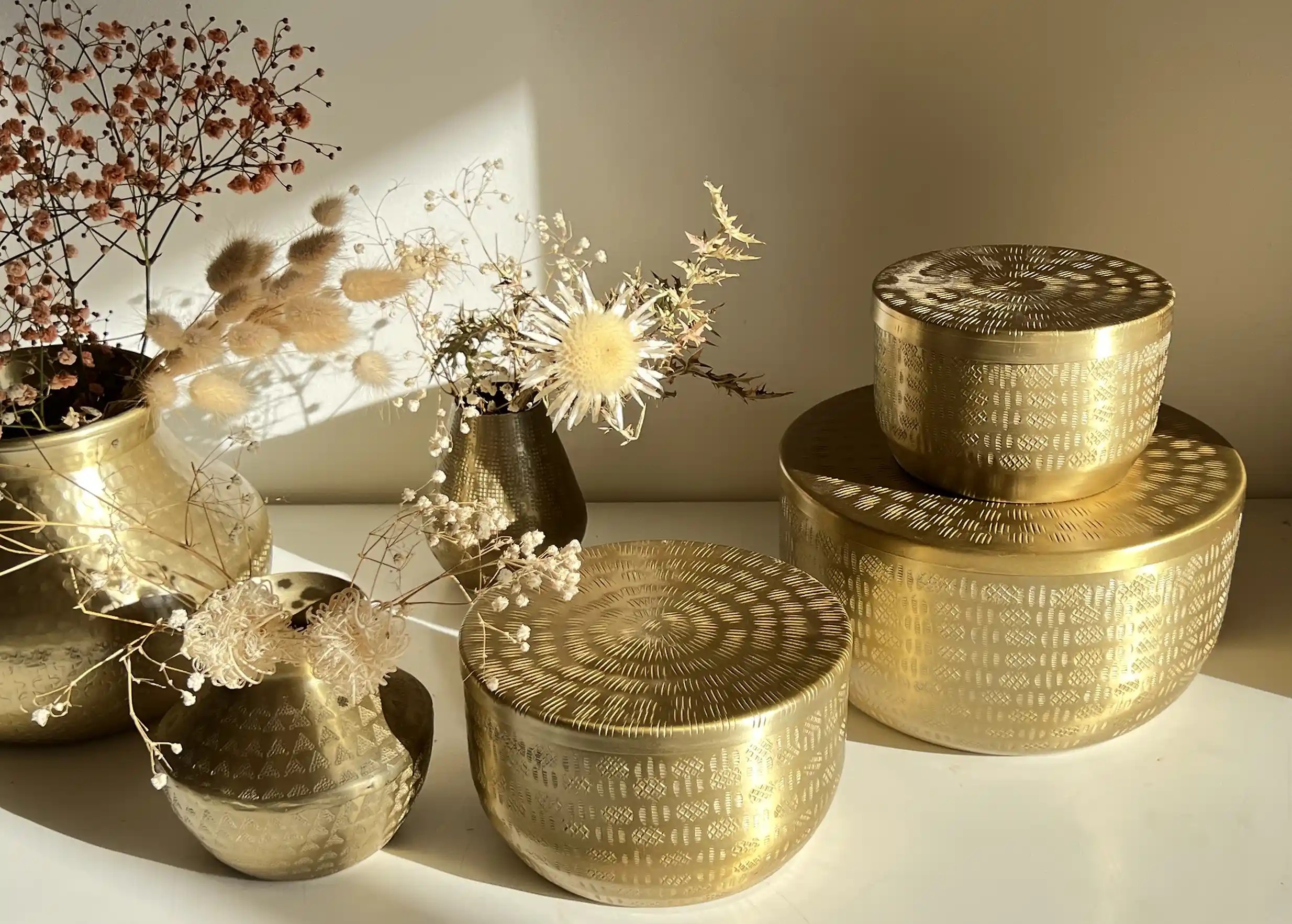 Recycled aluminium cans of various sizes stacked on top of each other, decorative plant by the wall