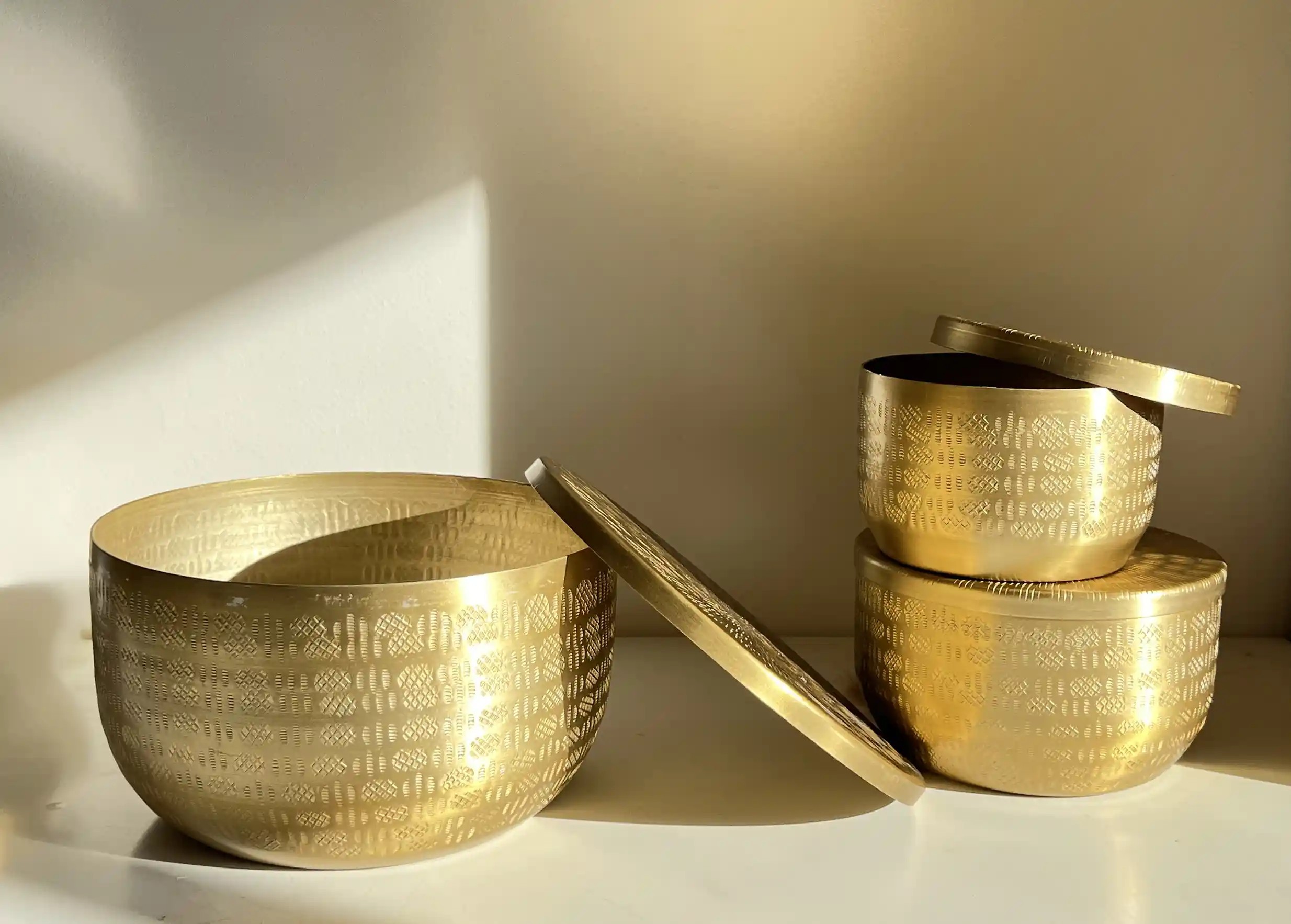 Boites en aluminium recyclé de diverses tailles empilées les unes sur les autres, près d'un mur blanc