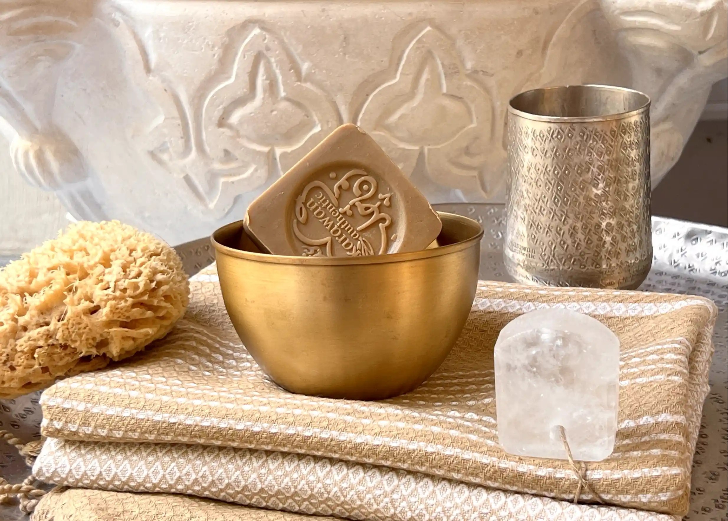 Savon d'Alep authentique dans un bon en laiton doré, éponge de mer, verre en laiton et pierre d'alun sur une fouta en coton
