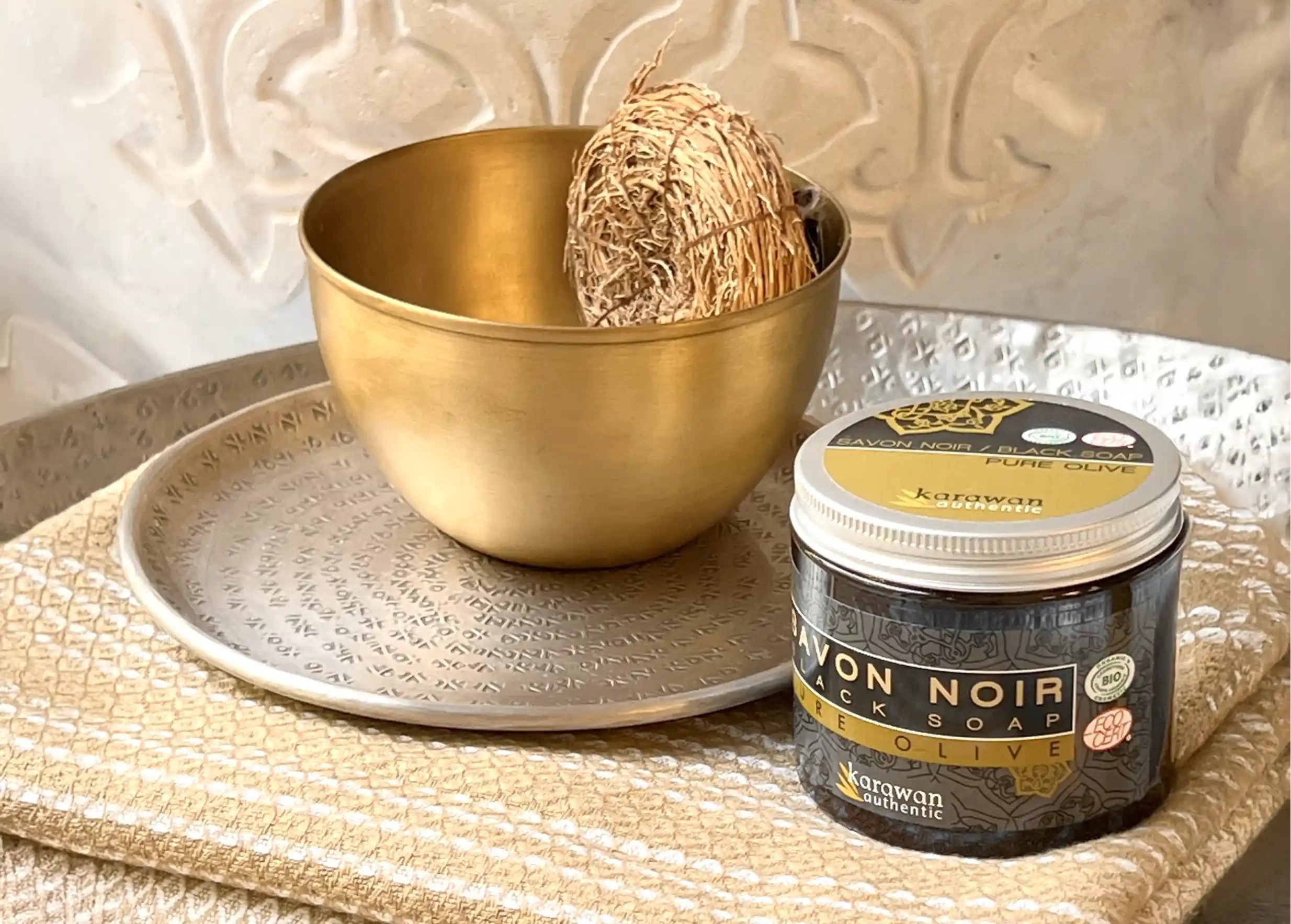 A vetiver sponge in a Moon gold brass bowl, set on a silver dish. Karawan black soap