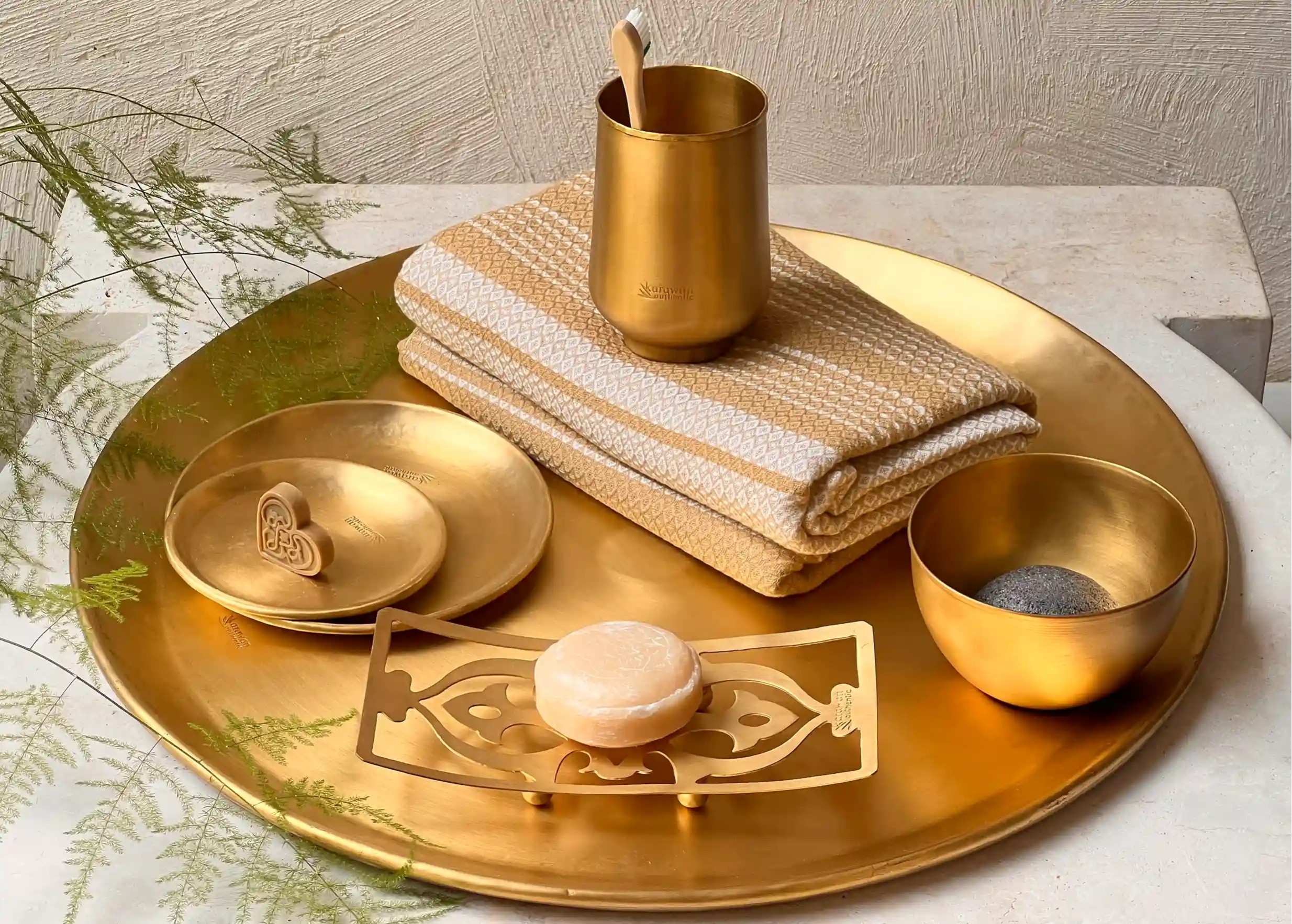 Verre en laiton doré lisse à côté d'une succession de pièces en laiton doré Moon : bols, verre, coupelles ou plateaux