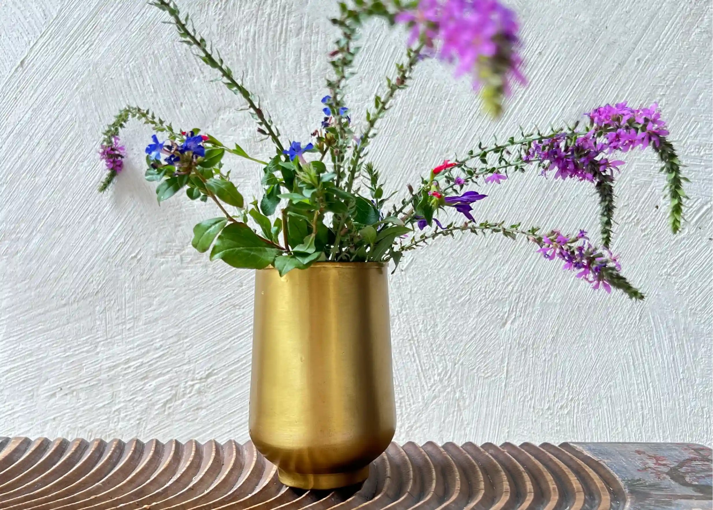 Verre en laiton lisse doré Moon contenant un bouquet de fleurs colorées et des feuillages verts