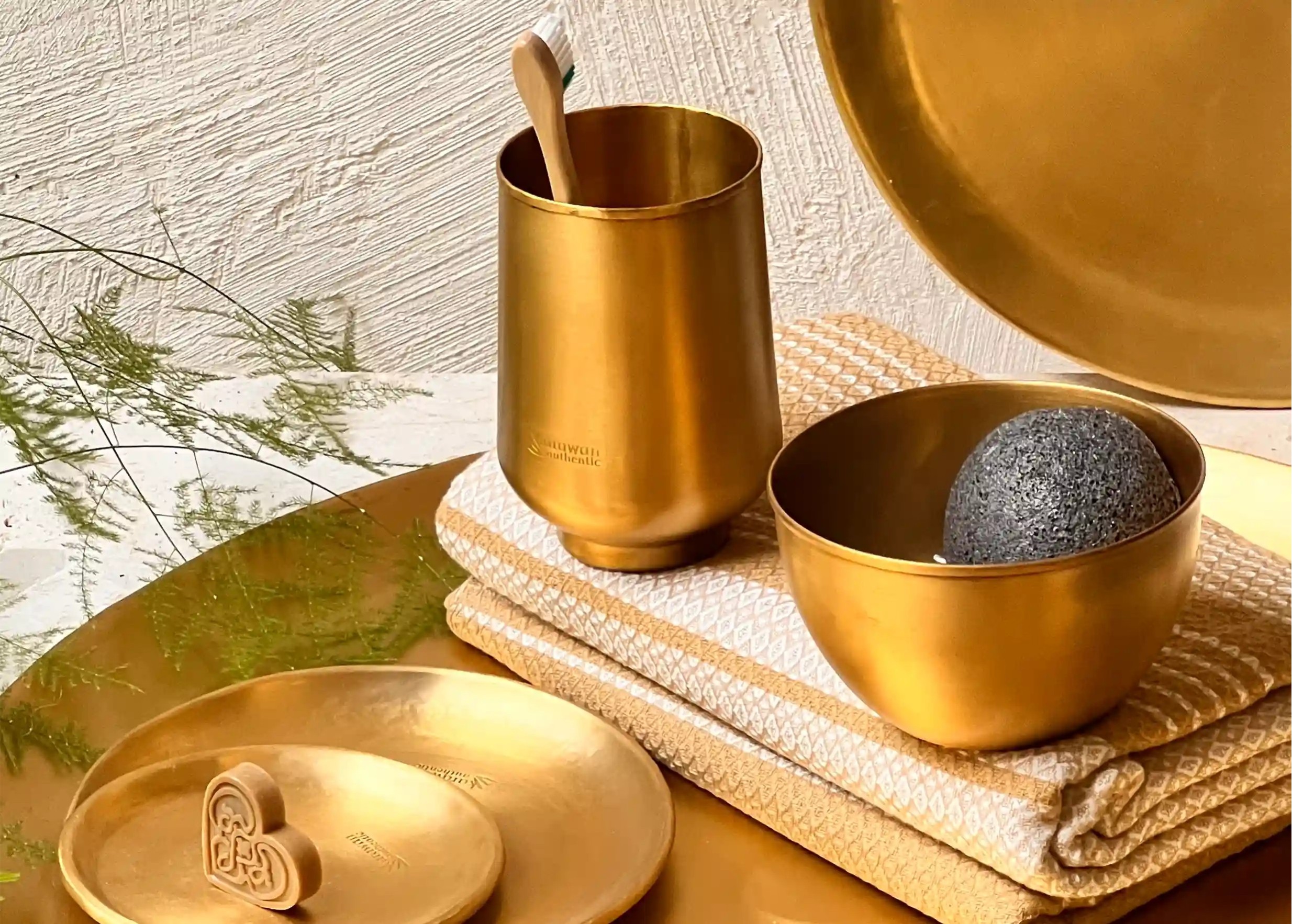 Collection en laiton doré avec un verre, un bol contenant une éponge, et une coupelle et un verre avec une brosse à dents