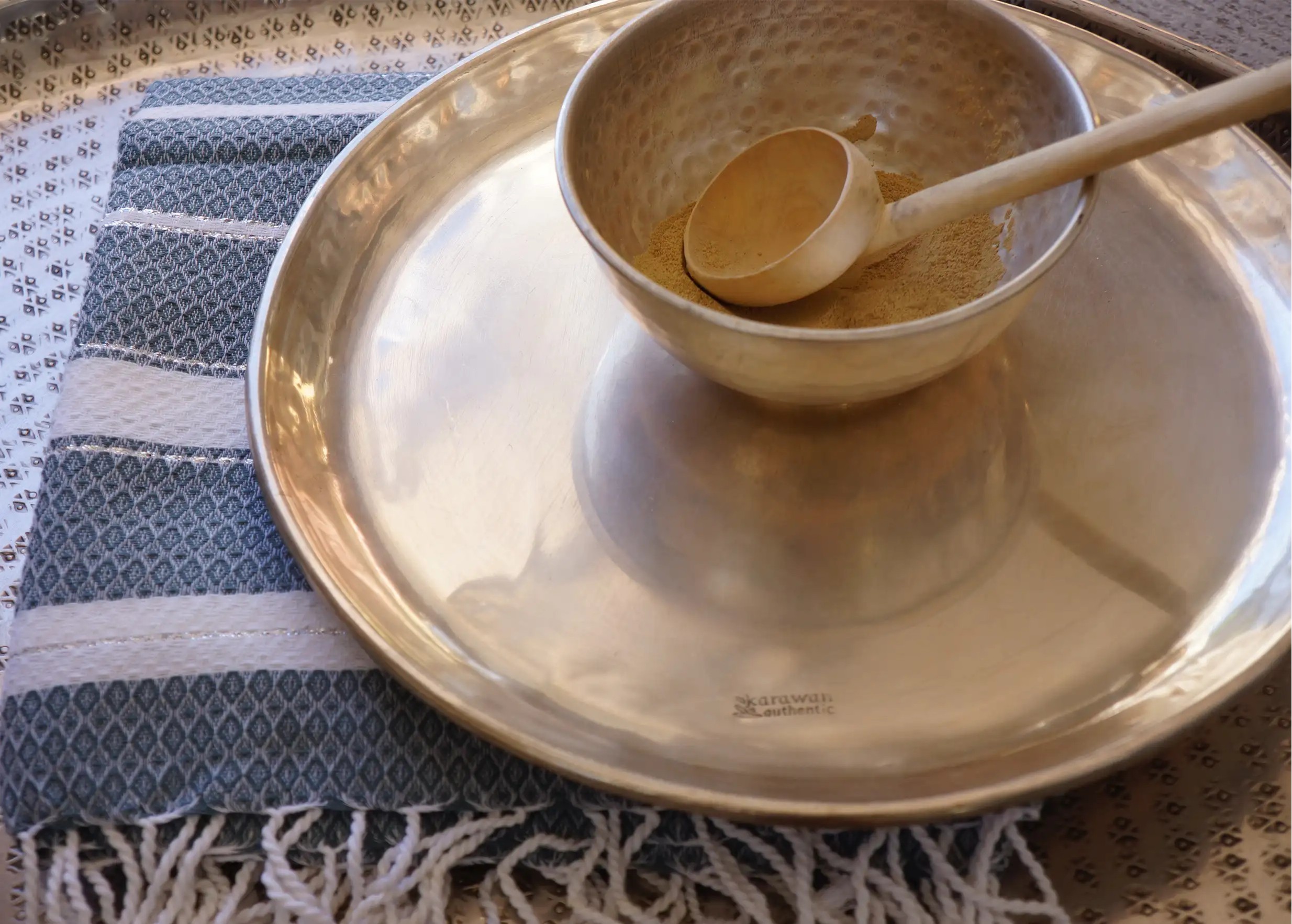 Plateau en laiton lisse et argenté Muz sur une fouta en coton bio rayée et de couleur bleue