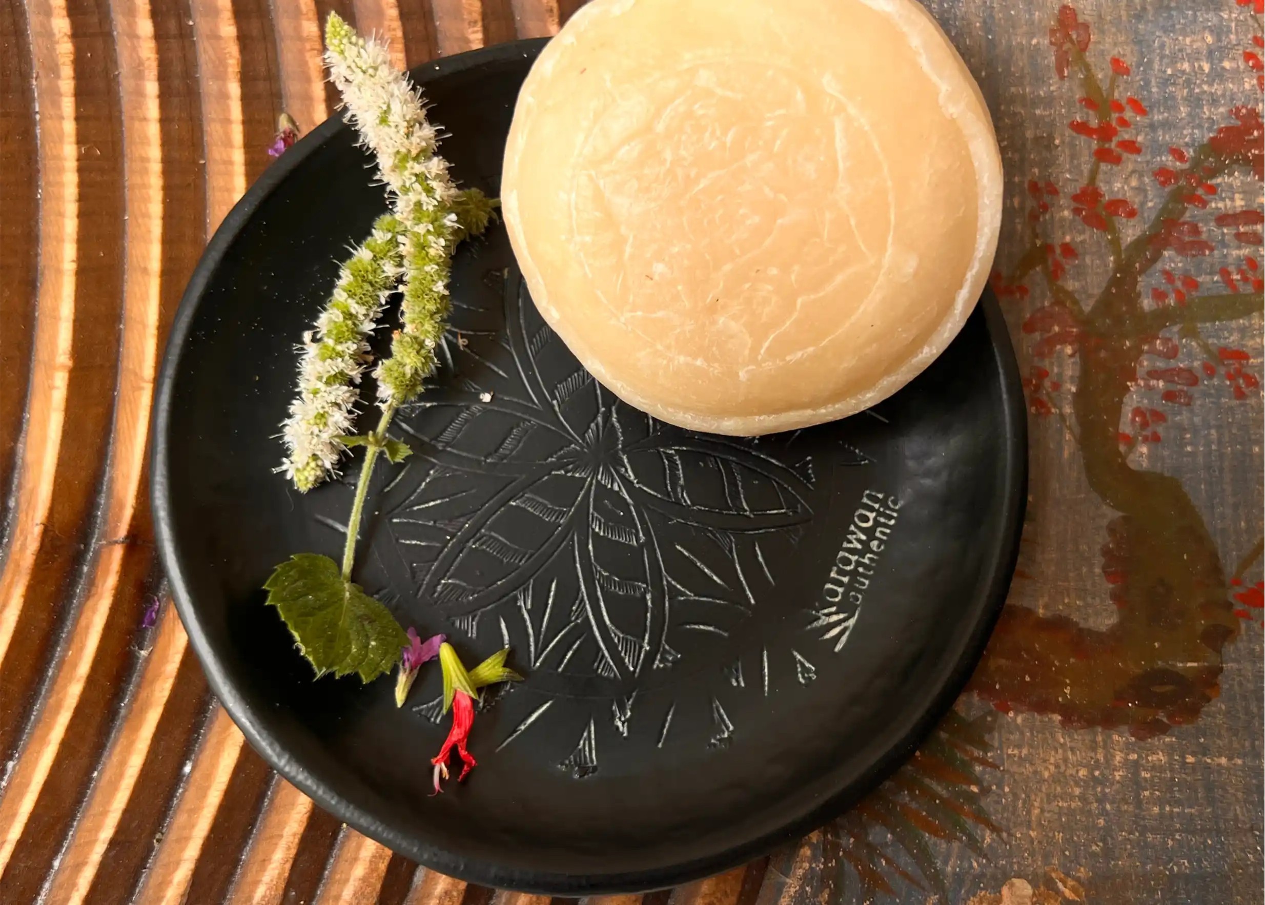 Savon ayurvédique posé sur une coupelle XXS noire en laiton oxydé et gravé Arabesk, posé sur une surface en bois texturée