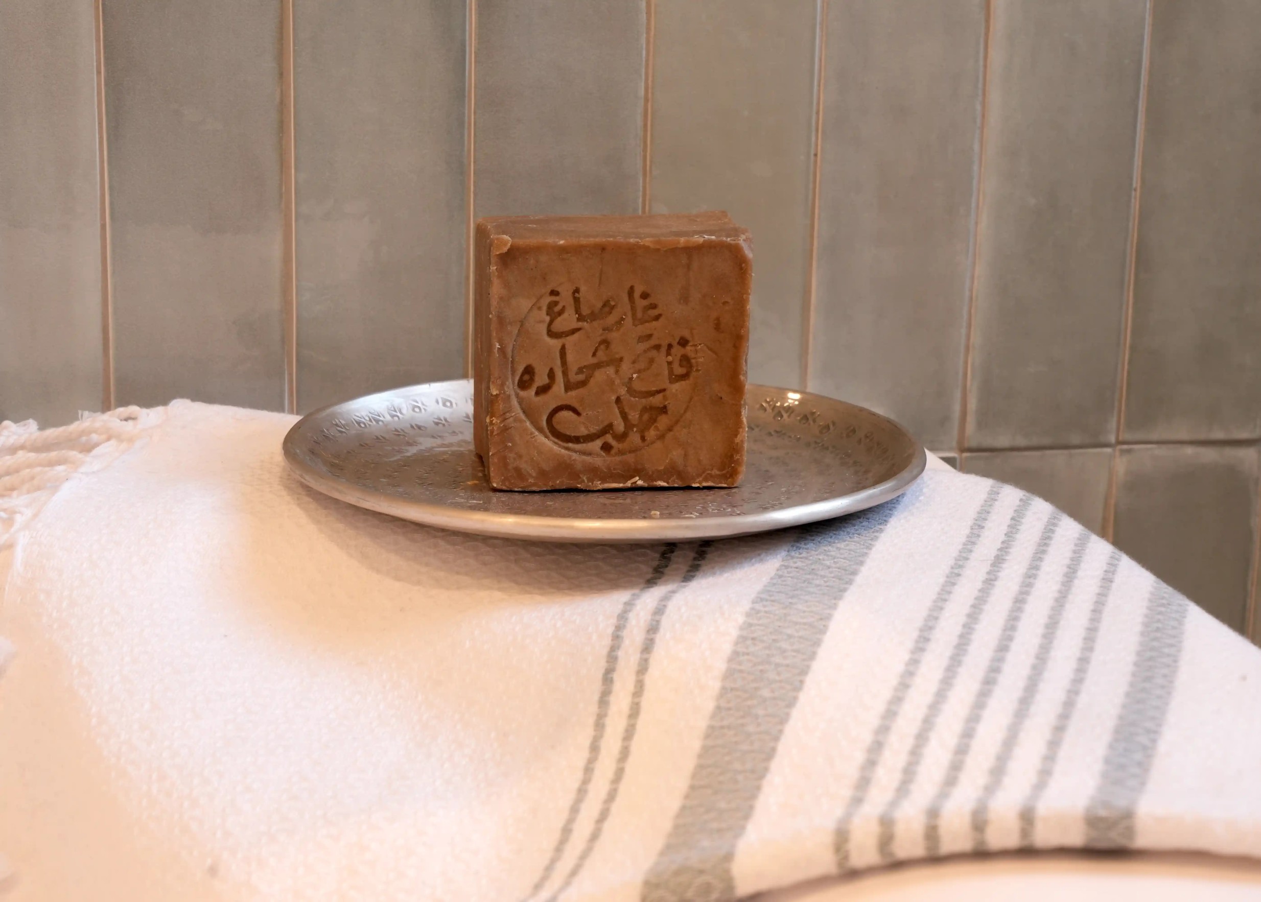 Petite coupelle ronde en laiton argenté martelé et gravé avec un savon solide, décorée de petites gravures