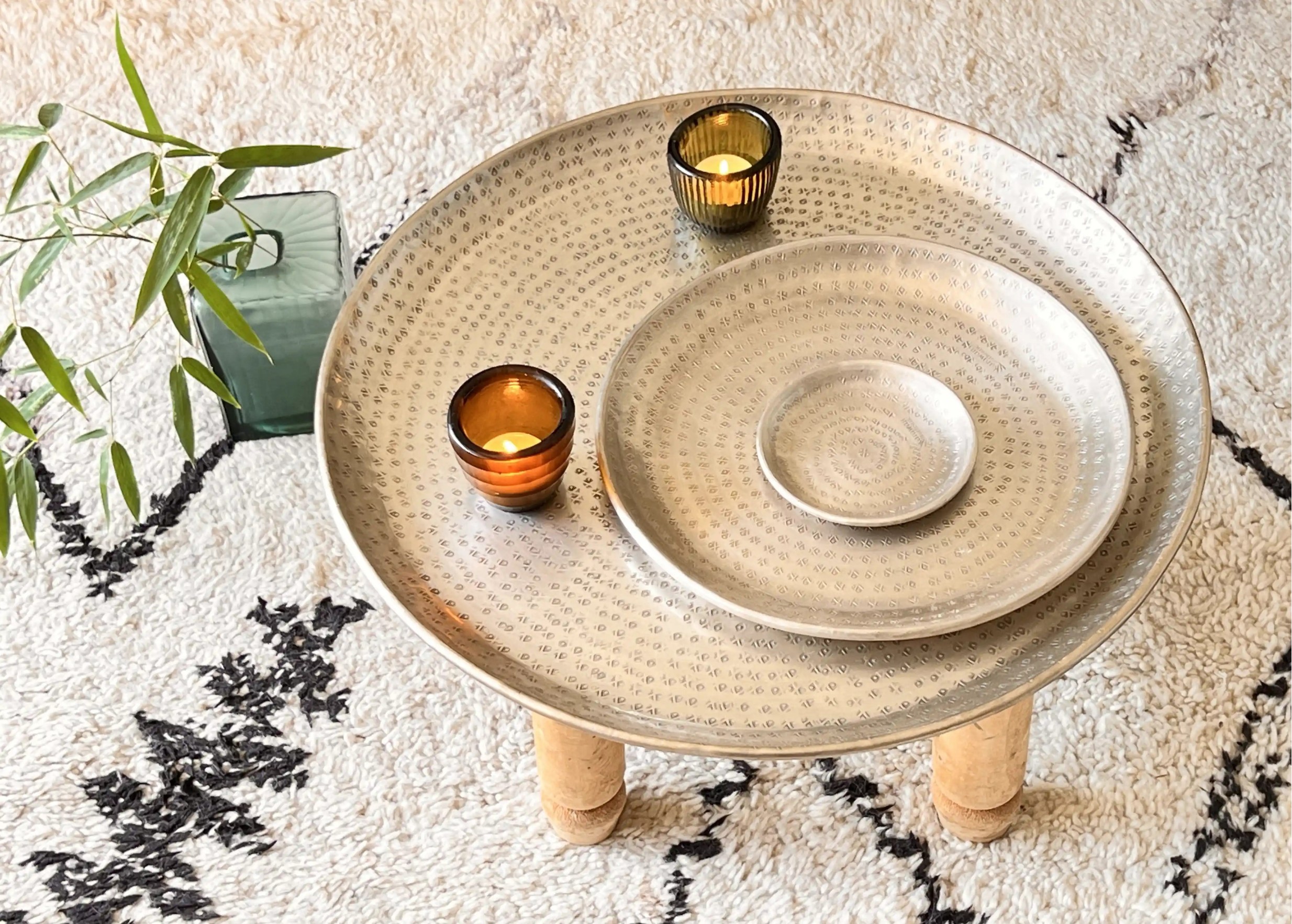 Set of silver-plated brass dishes arranged in ascending order of size, with a small glass candle-holder containing a candle.