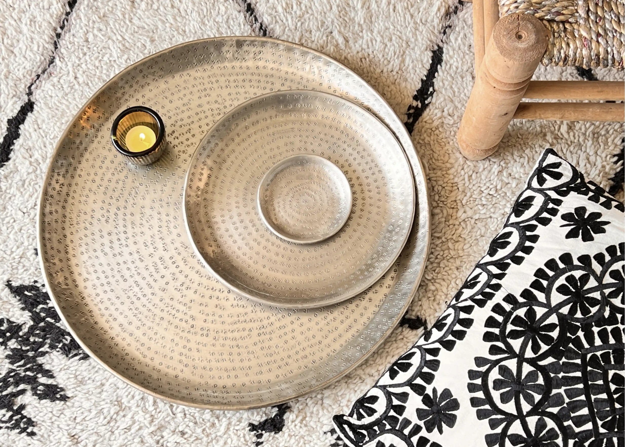 Coupelles en laiton argenté organisées par taille croissante, avec un petit photophore en verre contenant une bougie allumée