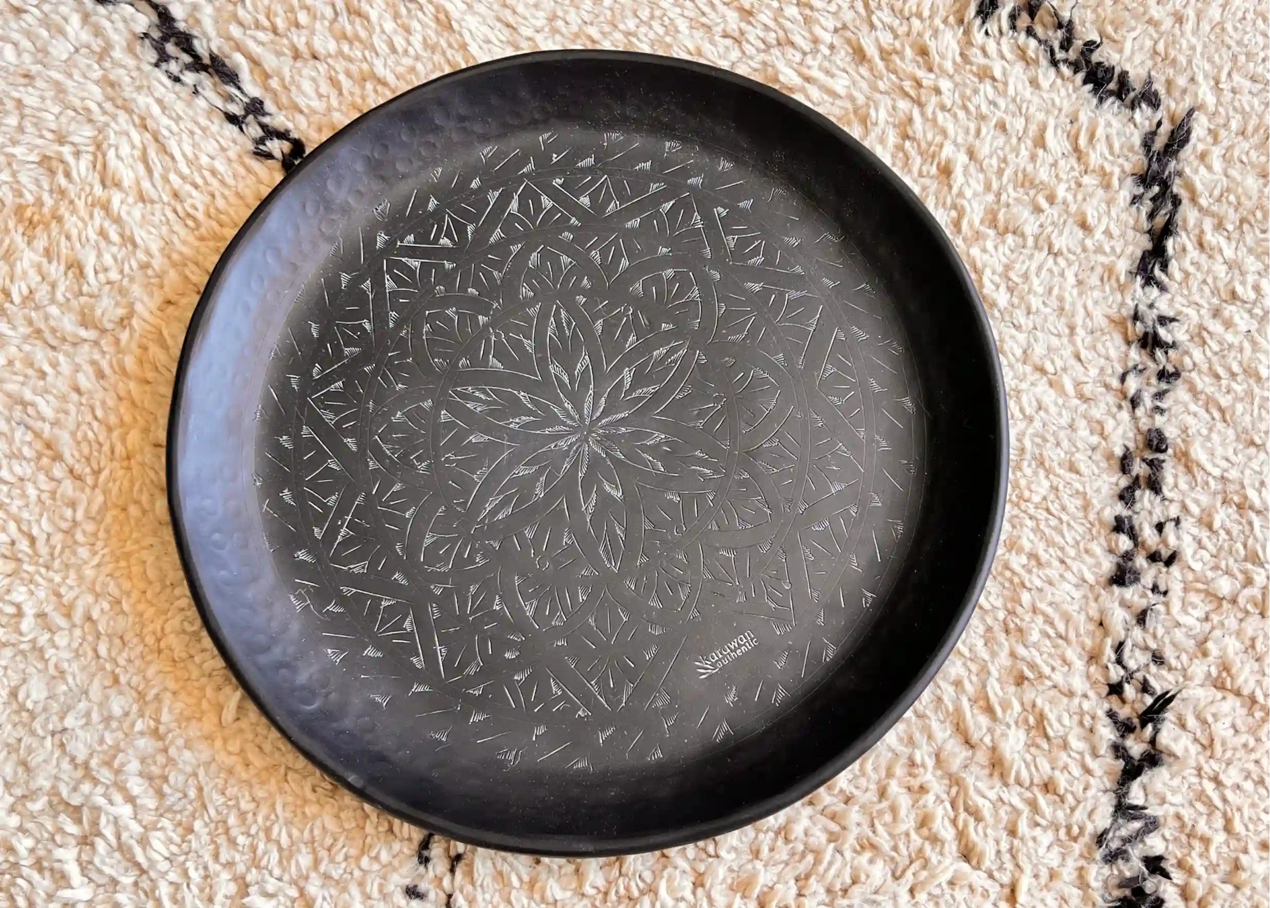 Zoom sur les finitions gravées d'un grand plateau noir en laiton Arabesk, photo prise de haut