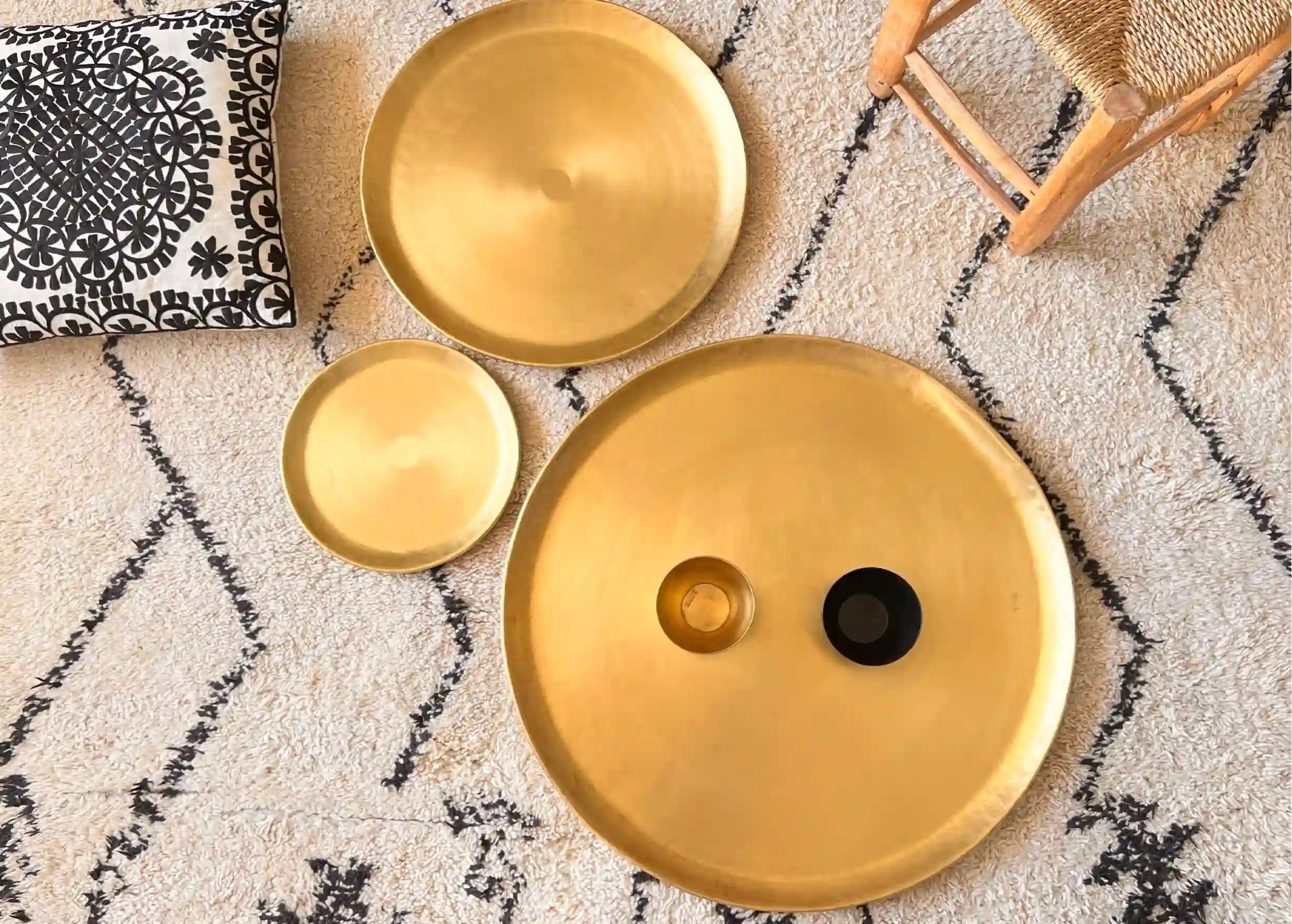 Ensemble déco en laiton doré, coussin blanc et noir aux motifs floraux, et tapis en toile de fond