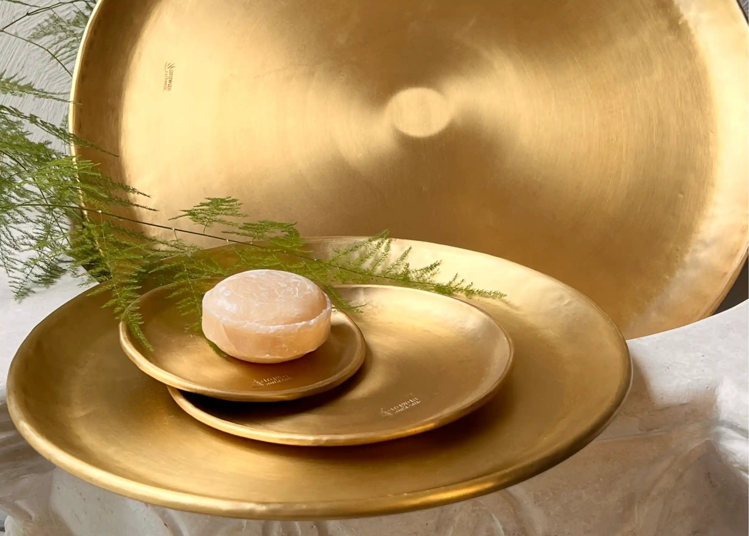 Petites coupelles en laiton posées sur un grand plateau en laiton lissé doré Moon, une de ces coupelles contient un savon