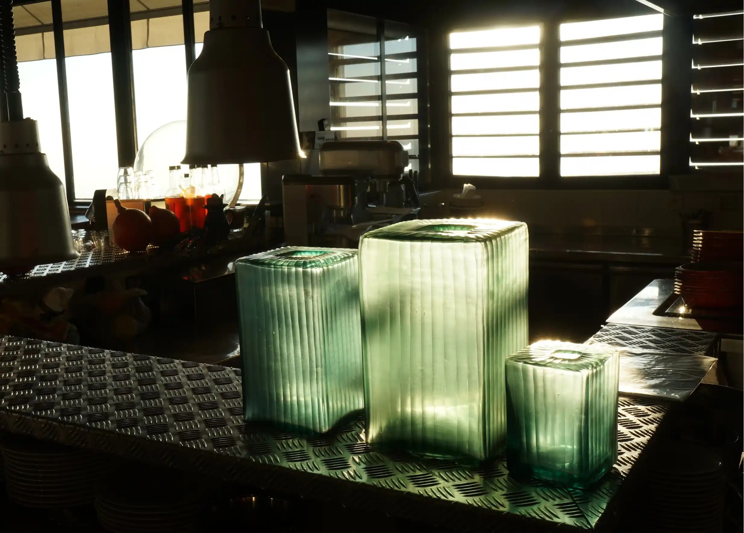 Set of three Aqua Cube vases in blown and recycled glass, in various sizes, a play of light and shade in a kitchen.