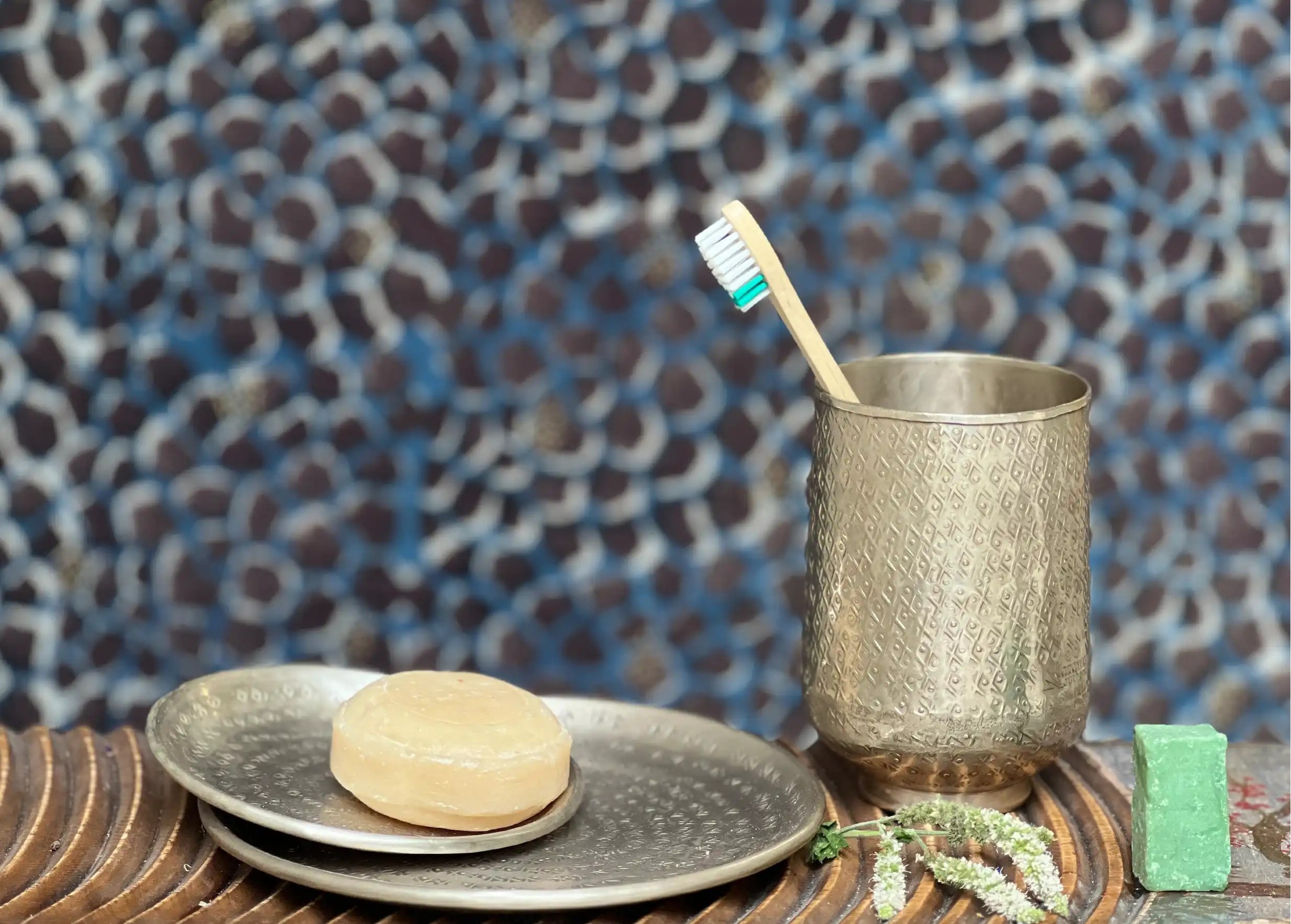 Silver-plated brass glass engraved with Palmyr containing a toothbrush, next to small brass dishes with a round bar of soap.