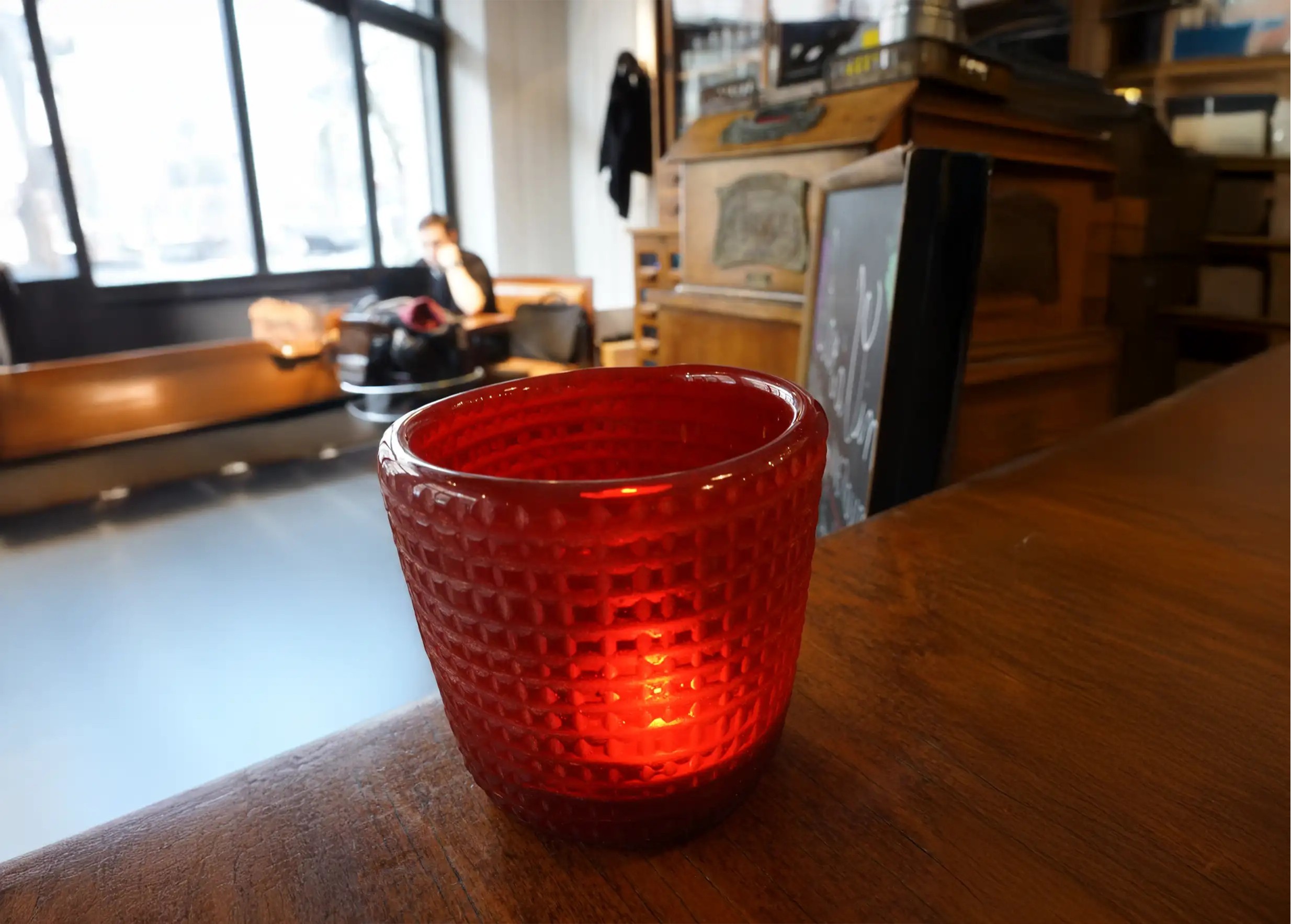 Ruby-colored blown glass tea light holder with a checkered texture, placed on an indoor wooden table