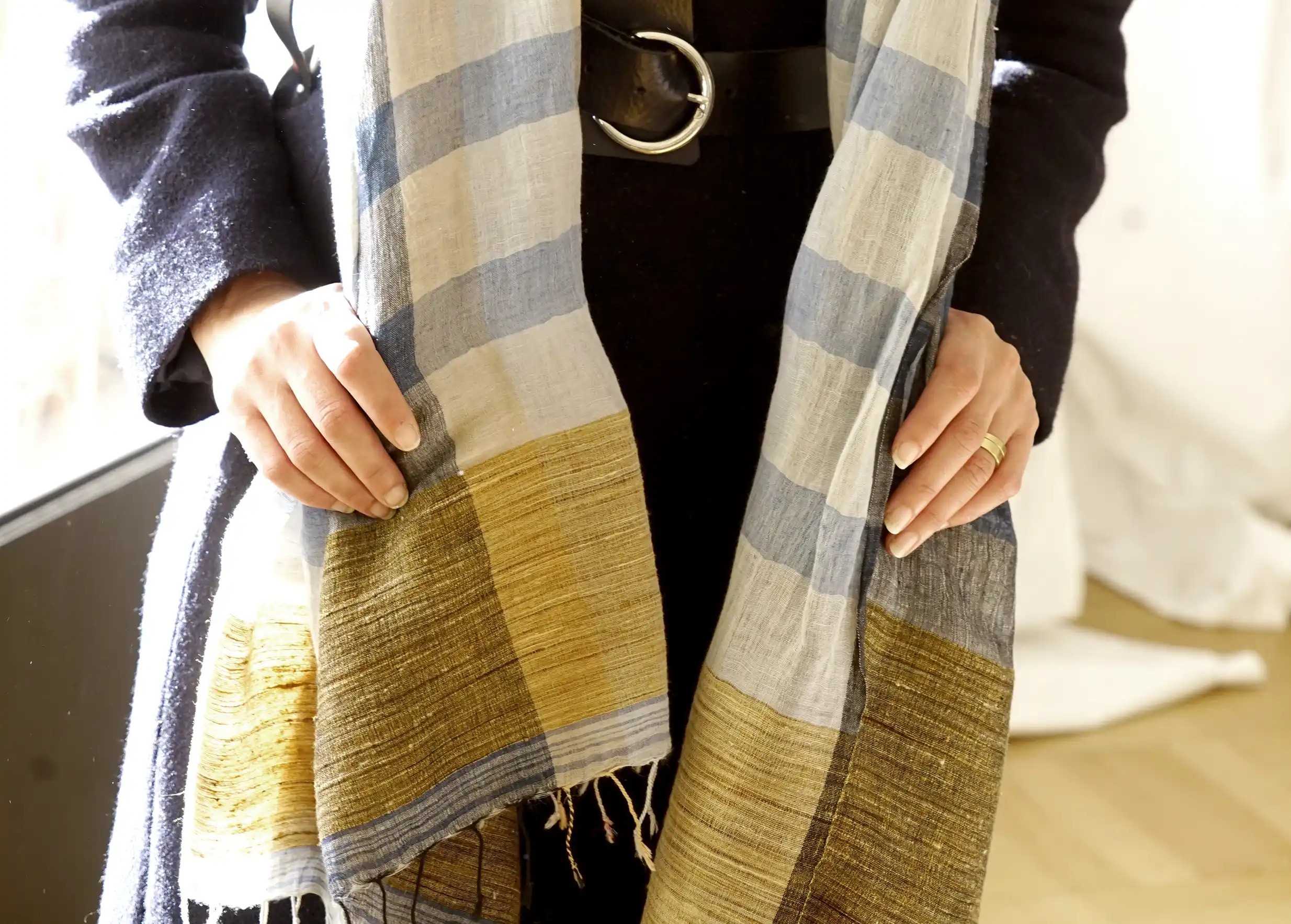 Femme portant sur les épaules une étole en lin, coton bio et jute, coloris bleu mirage, environnement indoor