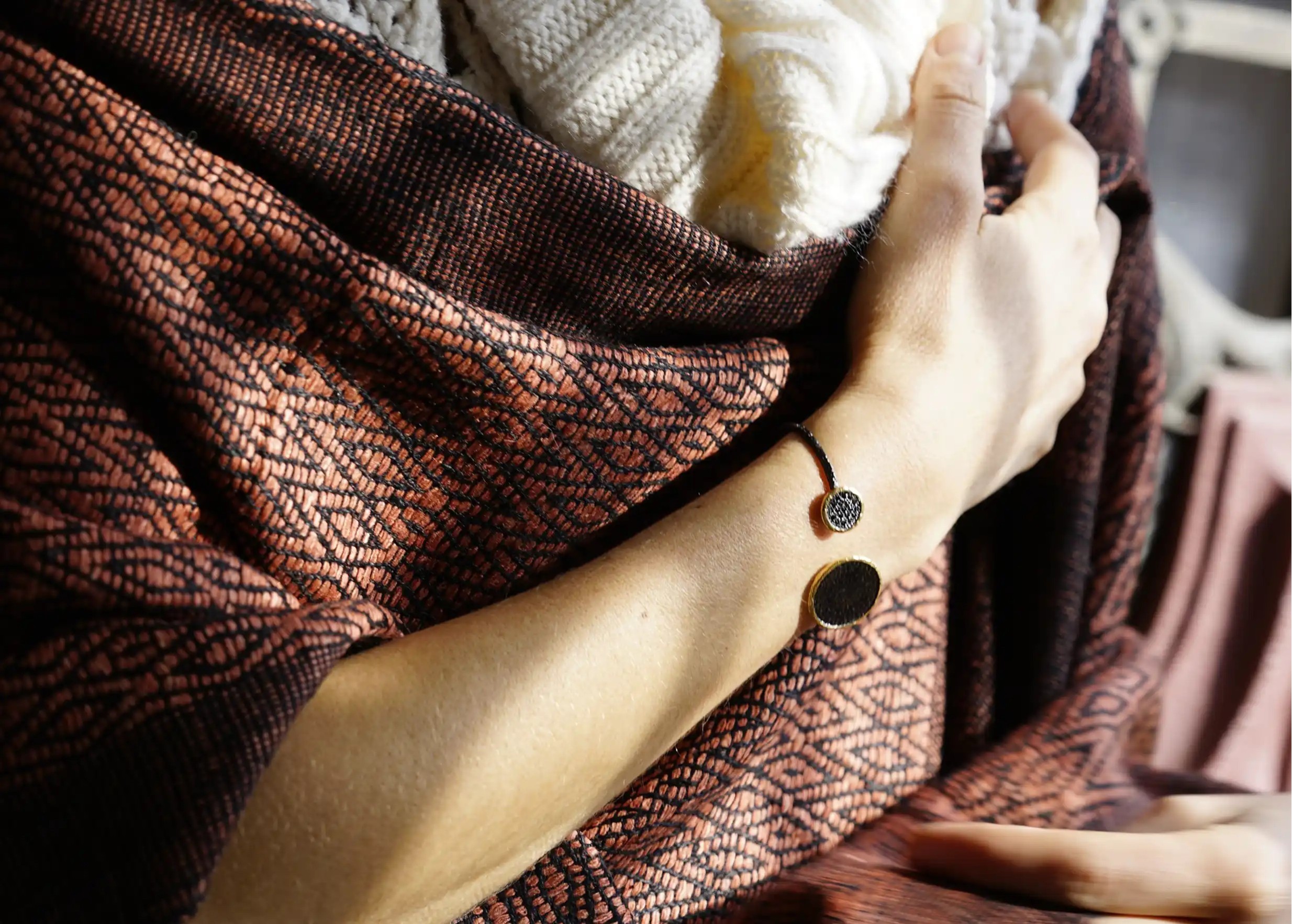 Zoom in on a clay-coloured wild silk stole, hand adorned with a Nuit des Temps gold bracelet