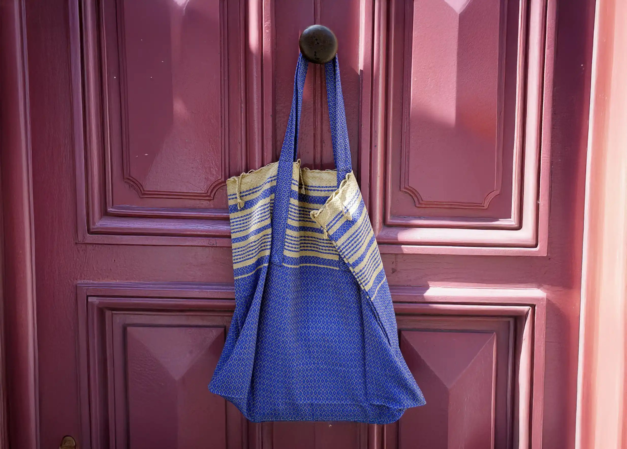 Foutabag en coton bio couleur bleu impérial, accroché devant une porte rouge