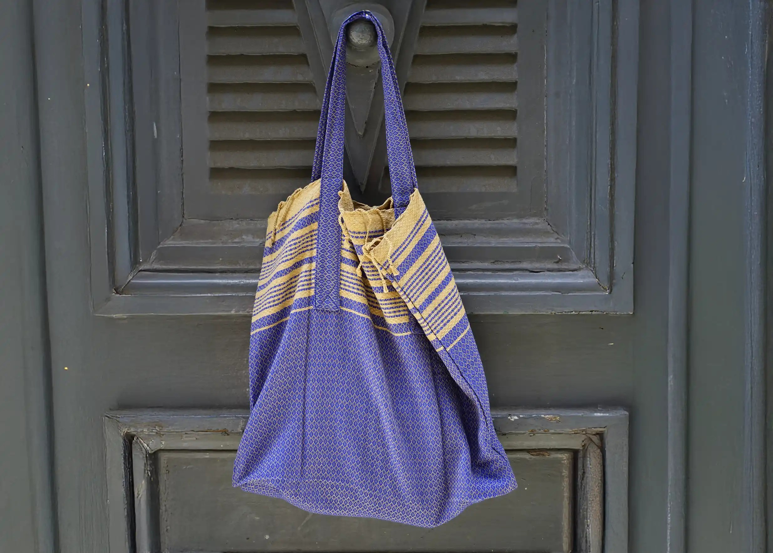 Foutabag in imperial blue organic cotton, hung in front of a black door