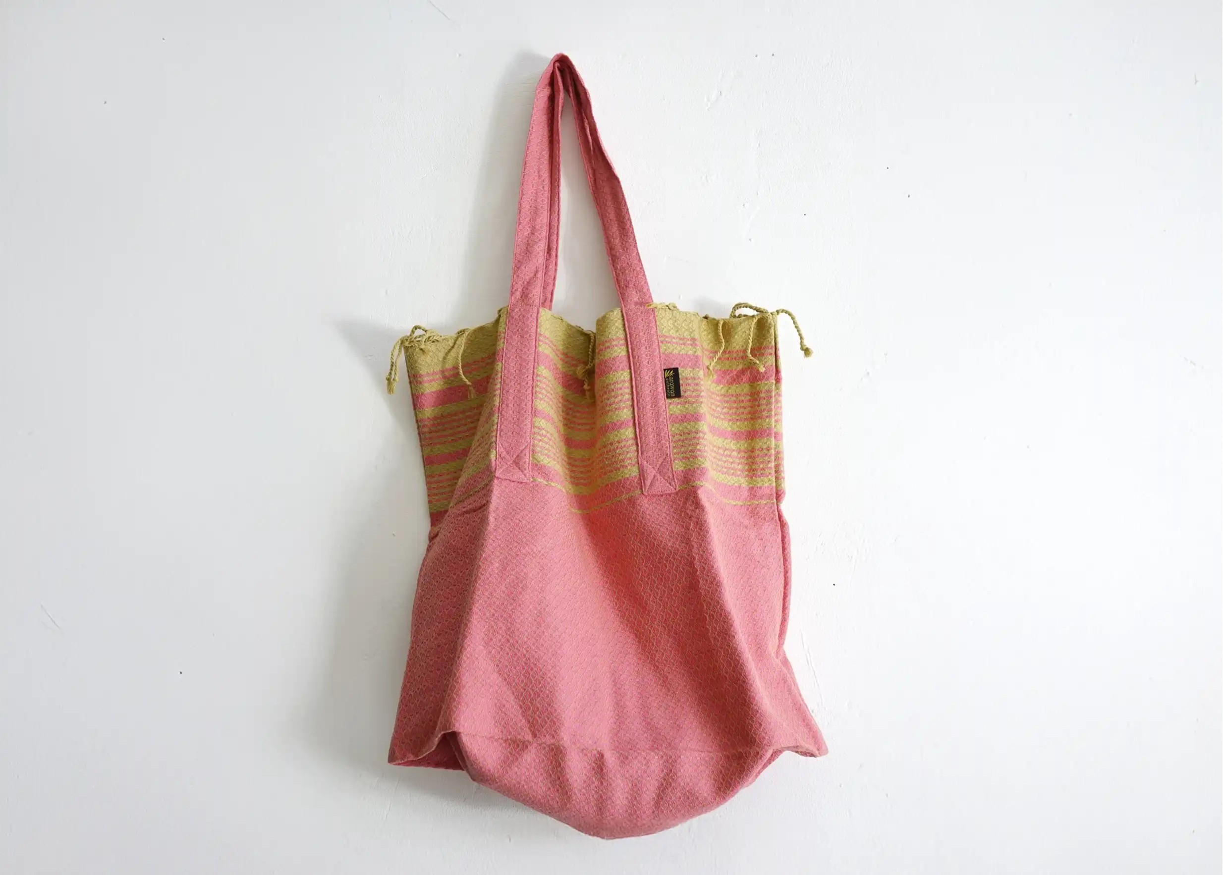 Foutabag in Indian pink organic cotton, hung in front of a plain wall