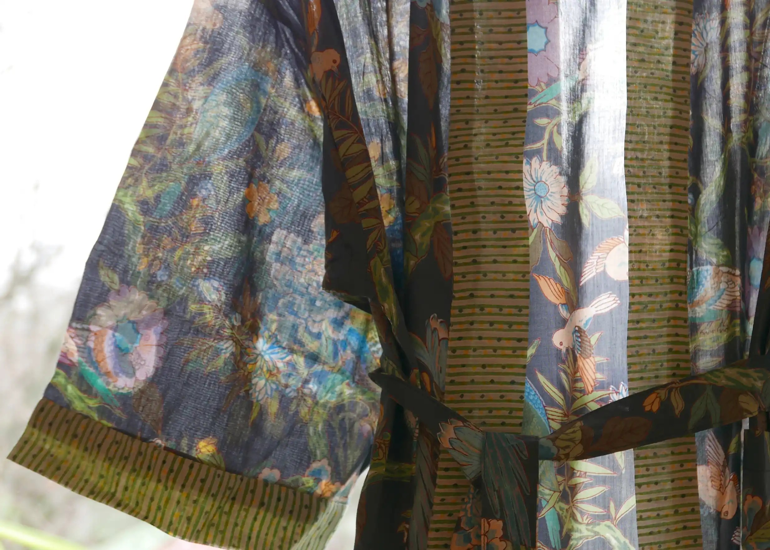 Gros plan sur le jeu de transparence du kimono en coton Paradise Bird, oiseaux colorés et feuillages