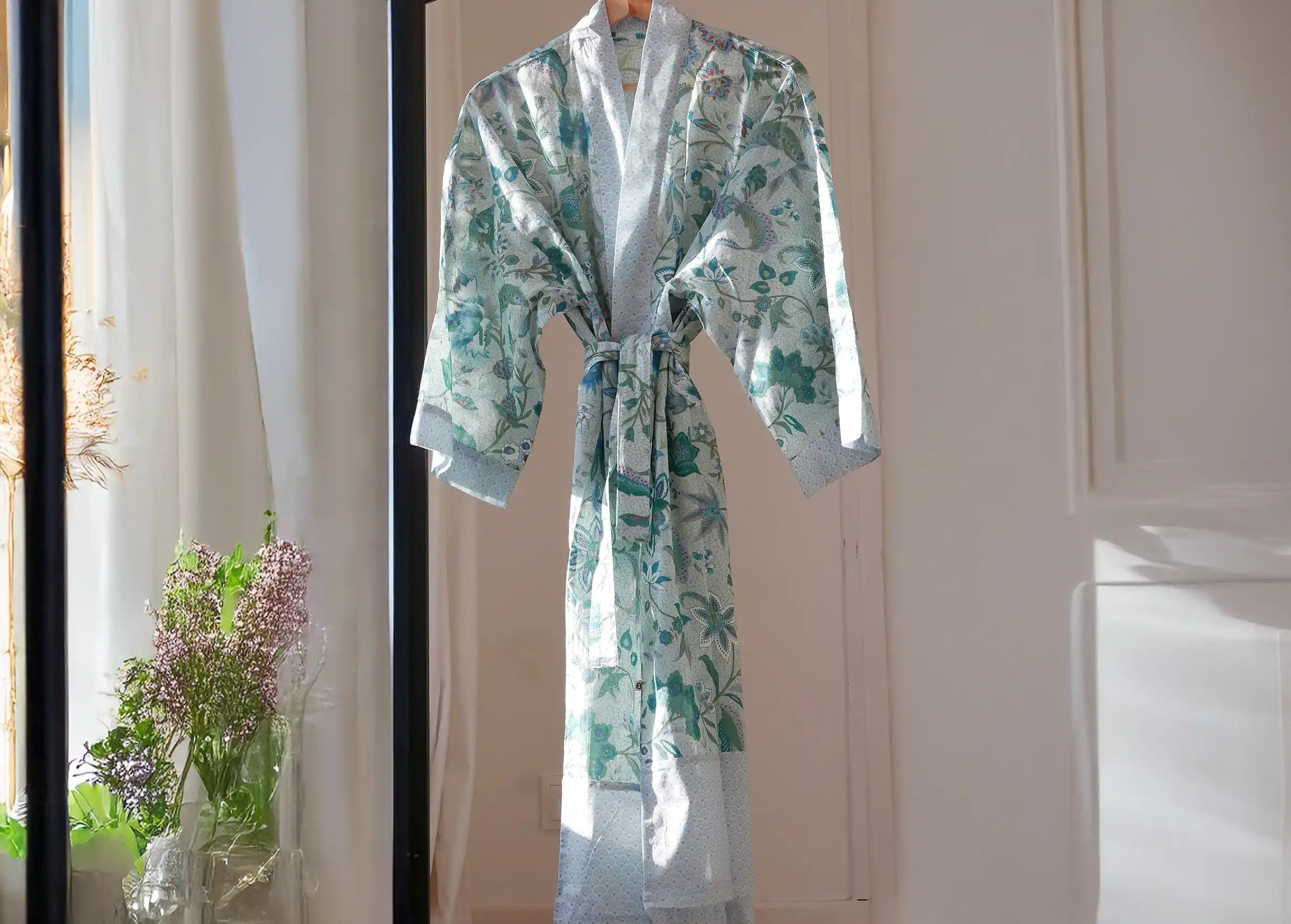 Blue Garden cotton kimono hanging on a wooden hanger, photo taken indoors