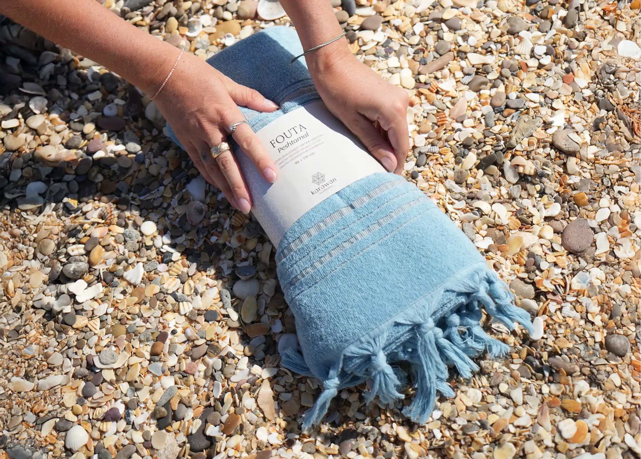 Fouta coloris Aigue Marine en coton bio sur un sol de coquillages