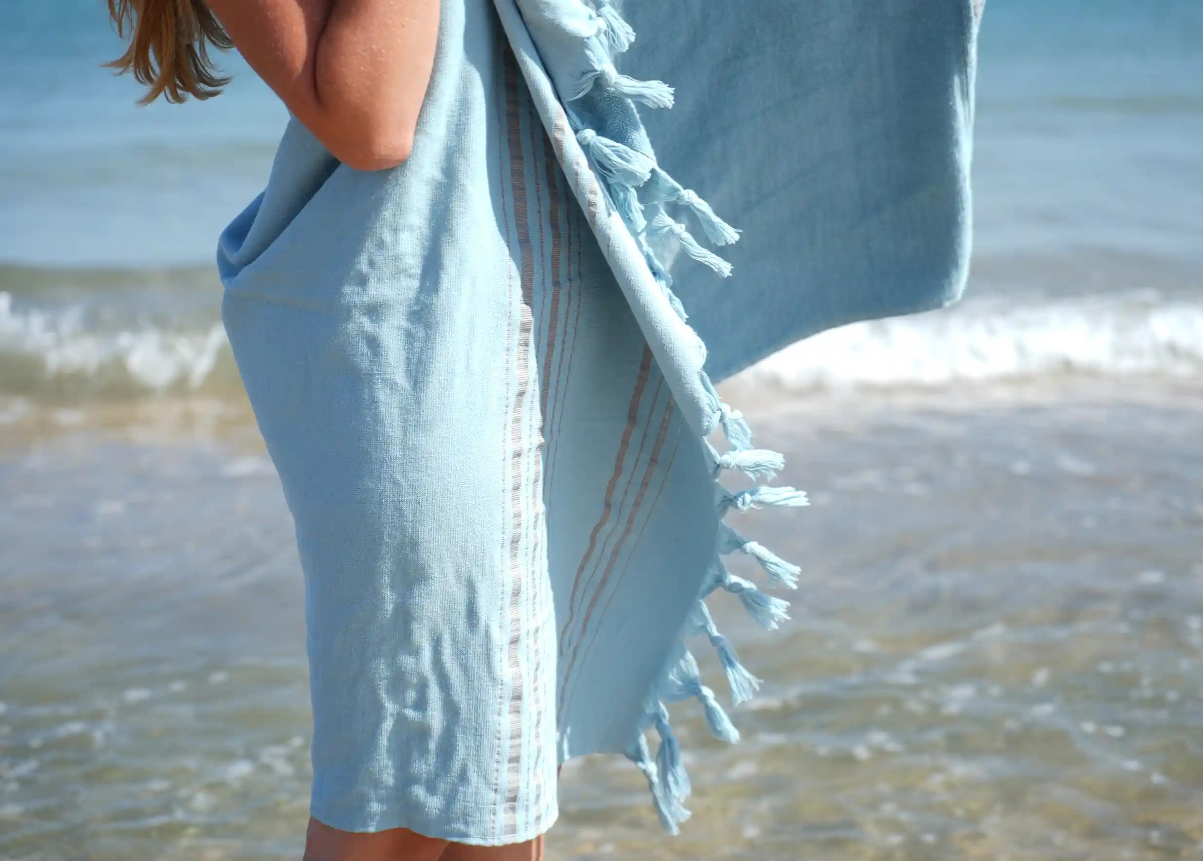 Femme dans une fouta coloris Aigue Marine en coton bio au bord de la mer