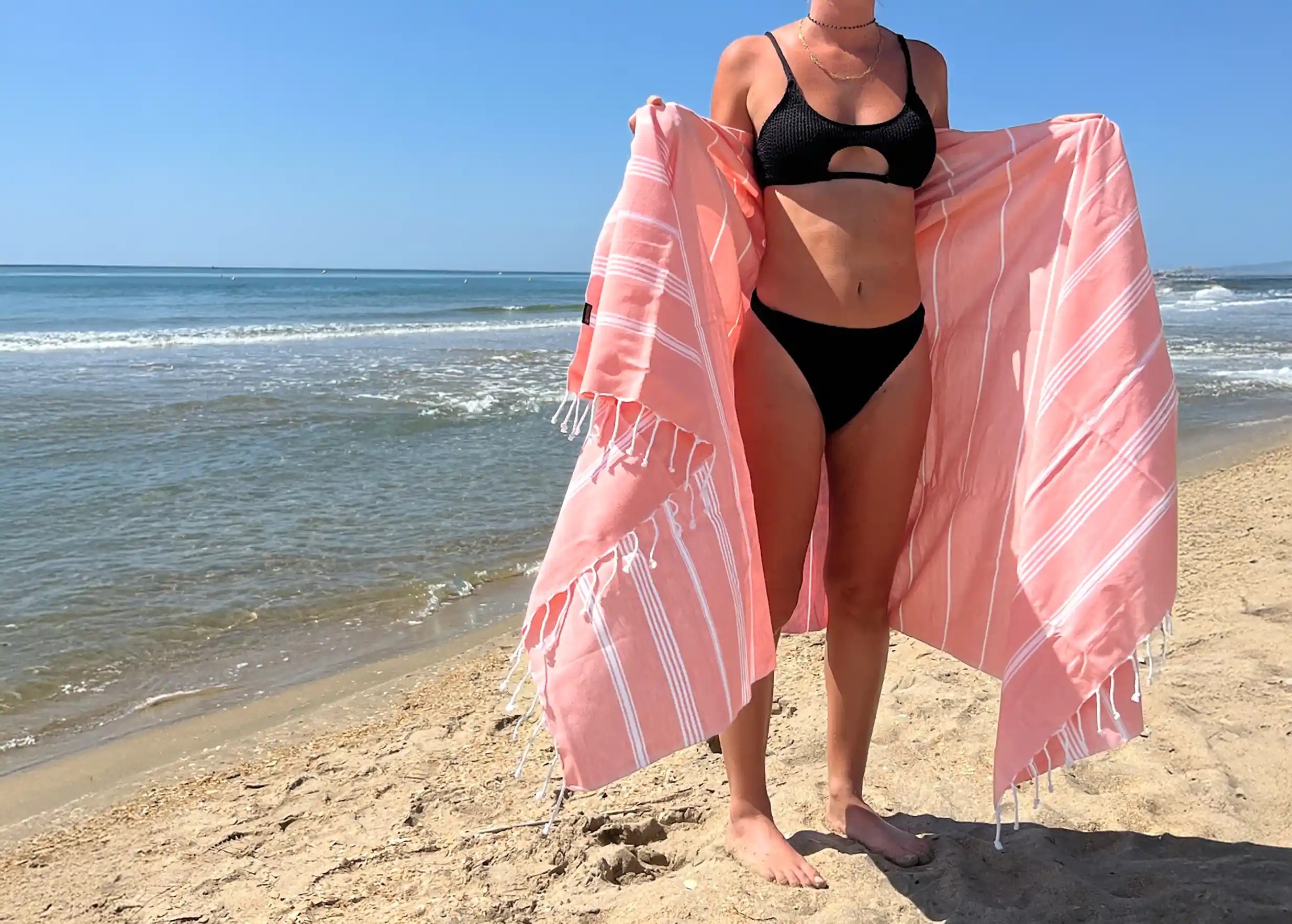 Femme à la plage portant une fouta en coton bio de la collection Hammam Femme à la plage portant une fouta en coton bio de la collection Hammam