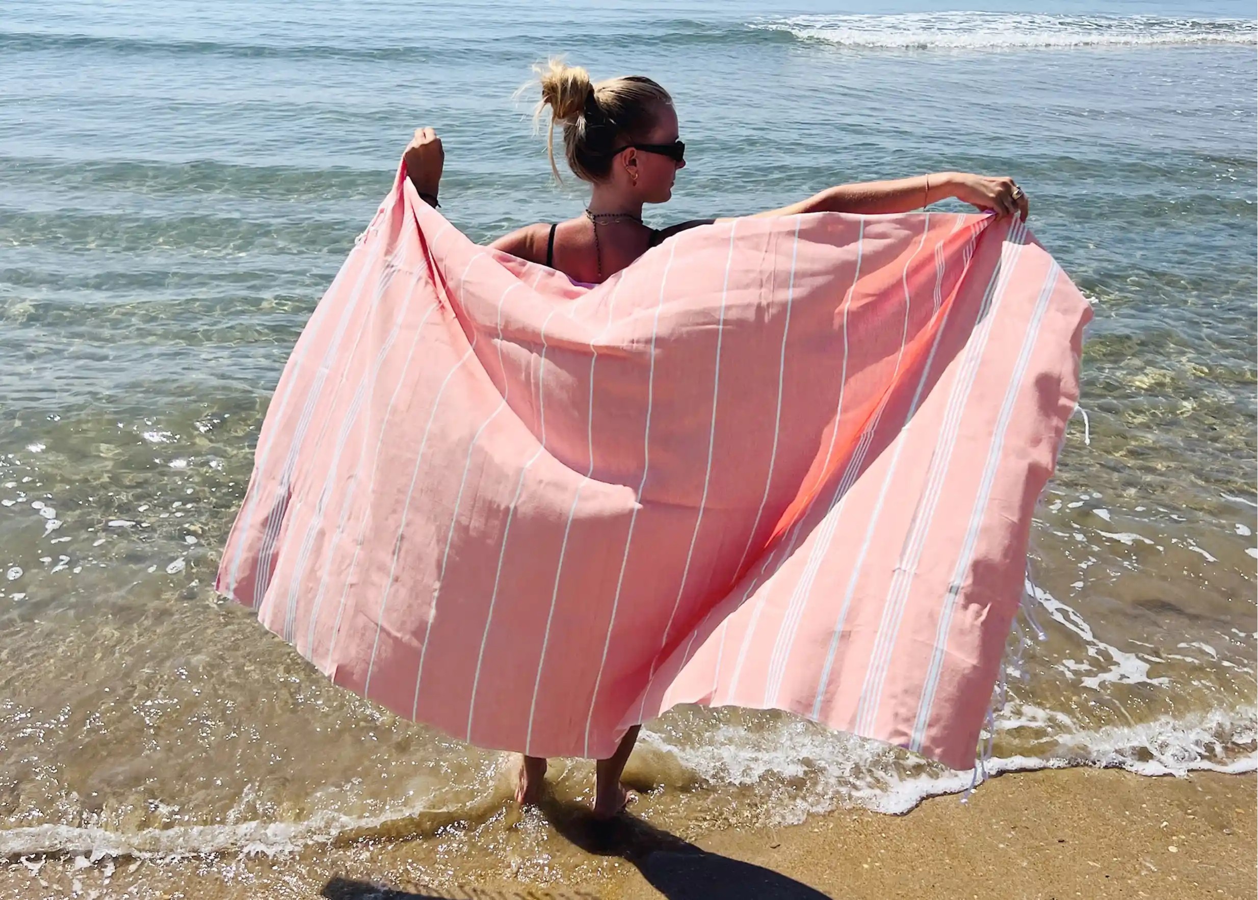 Femme de dos, portant une foutant coloris corail, collection Hammam Femme de dos, portant une foutant coloris corail, collection Hammam