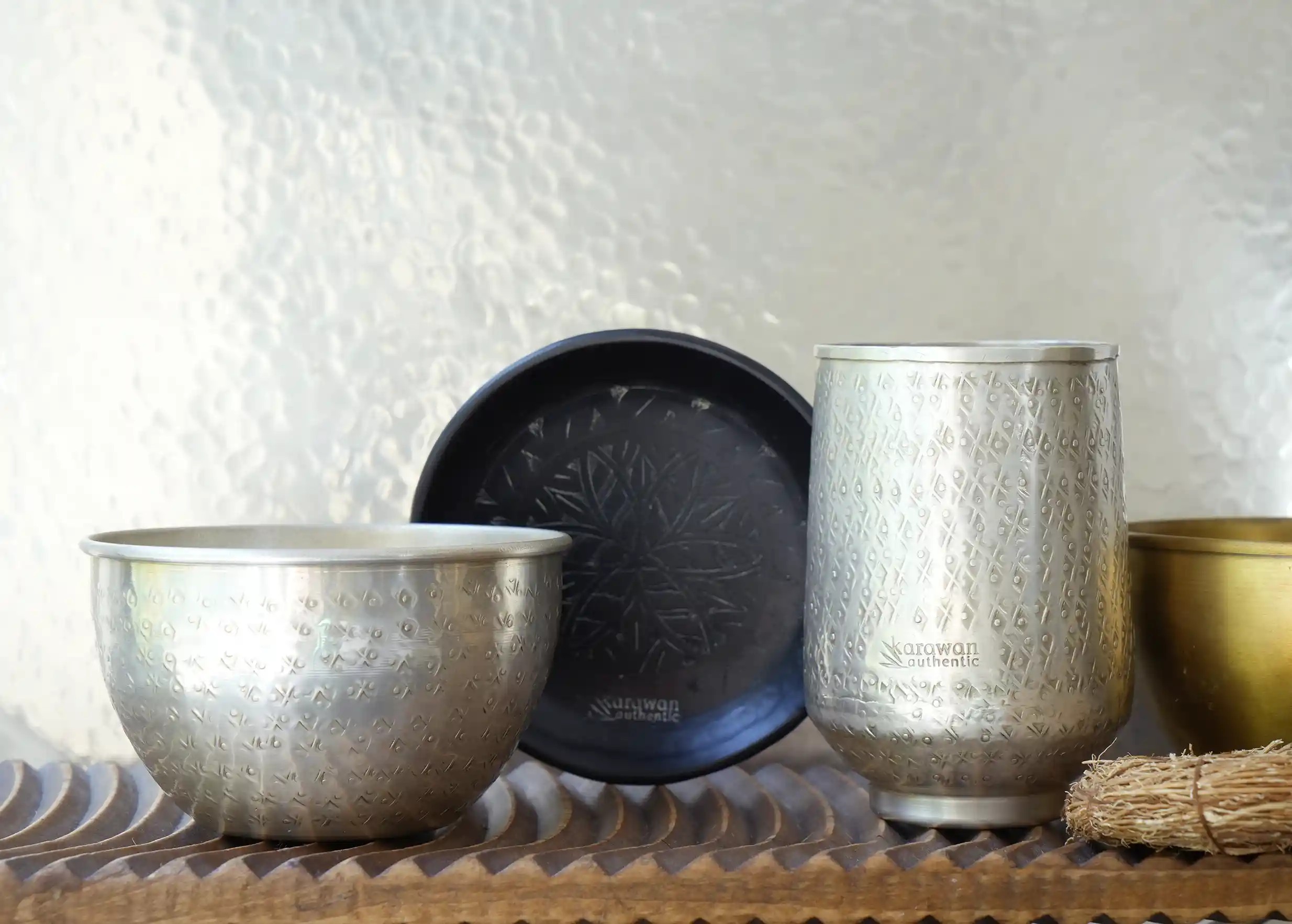 Collection d'objets déco en laiton, bol en laiton argenté, plateaux en arrière-plan, de la marque Karawan