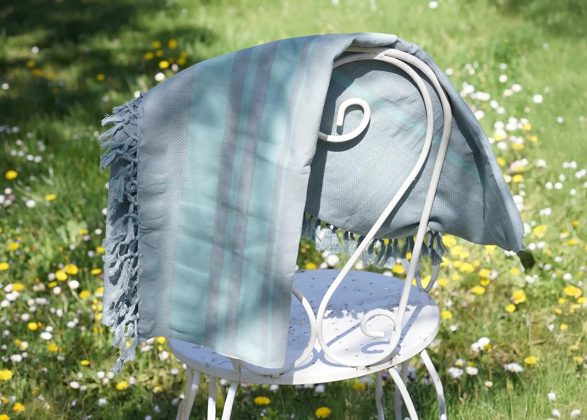 Lightweight, blue organic cotton fouta on a small outdoor chair