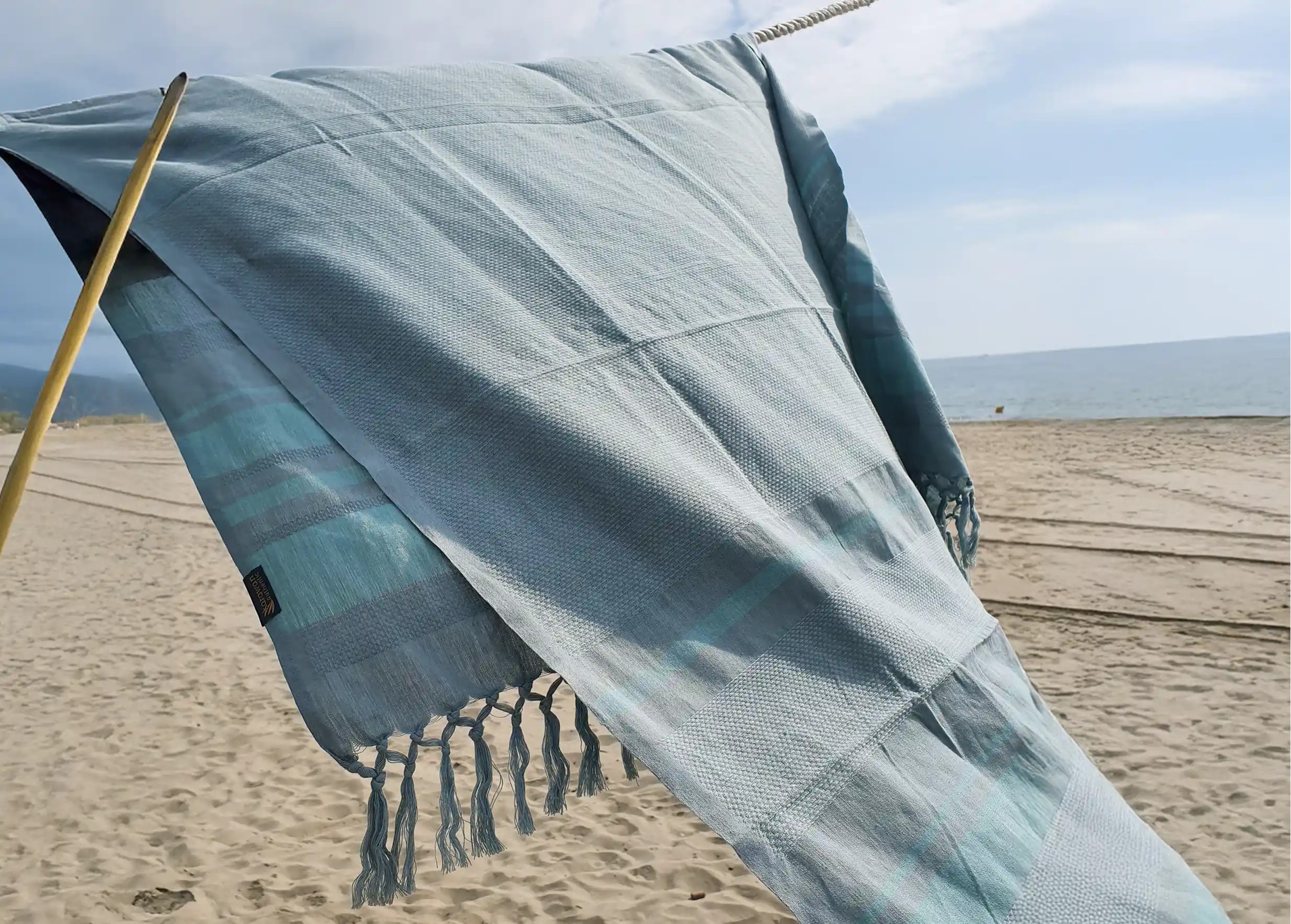 Fouta en coton bio au coloris Almond, issue de la collection Garden, le souffle du vent sur une plage