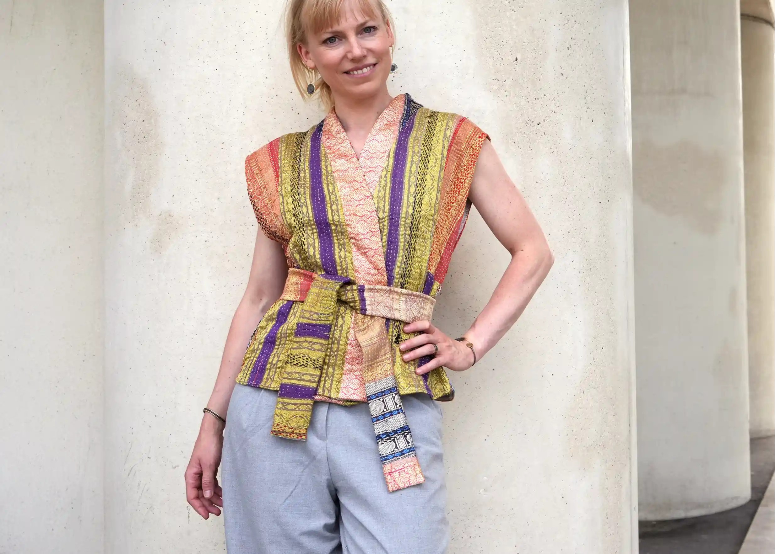 Femme posée contre un mur portant un gilet en soie et coton kanta matelassé