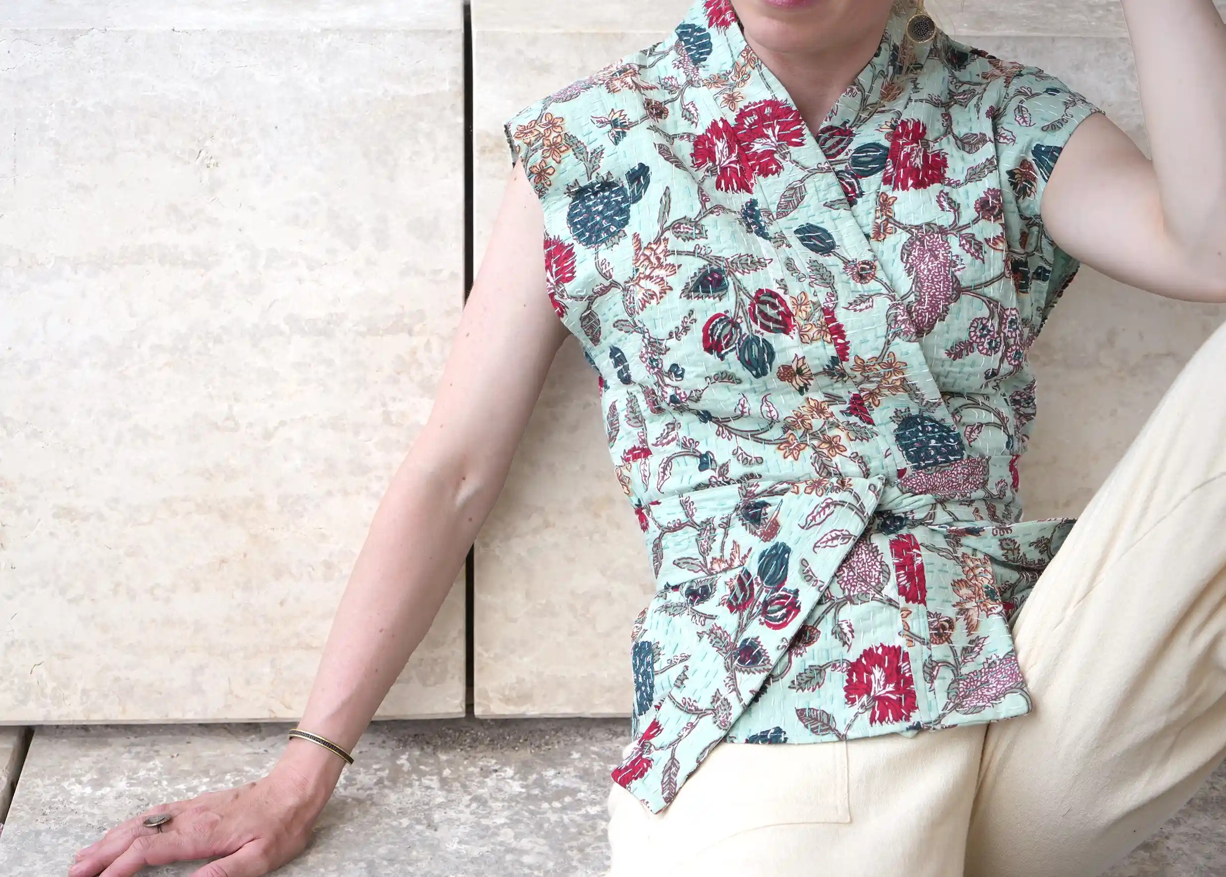 Woman against a wall wearing a quilted cotton kimono vest from the Karawan Authentic brand.
