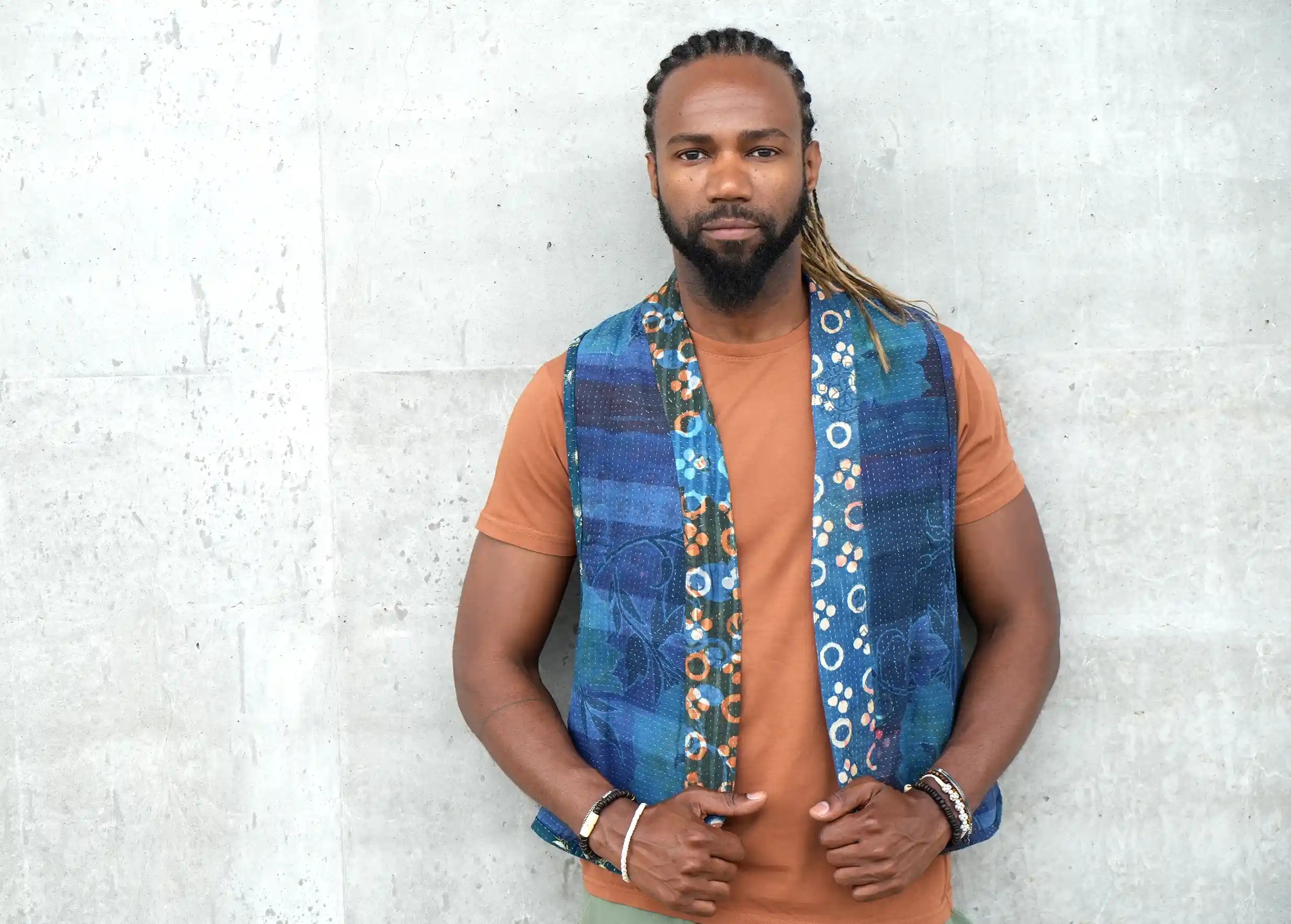 Man against a wall, holding his reversible quilted cotton kanta beloro by his fingertips