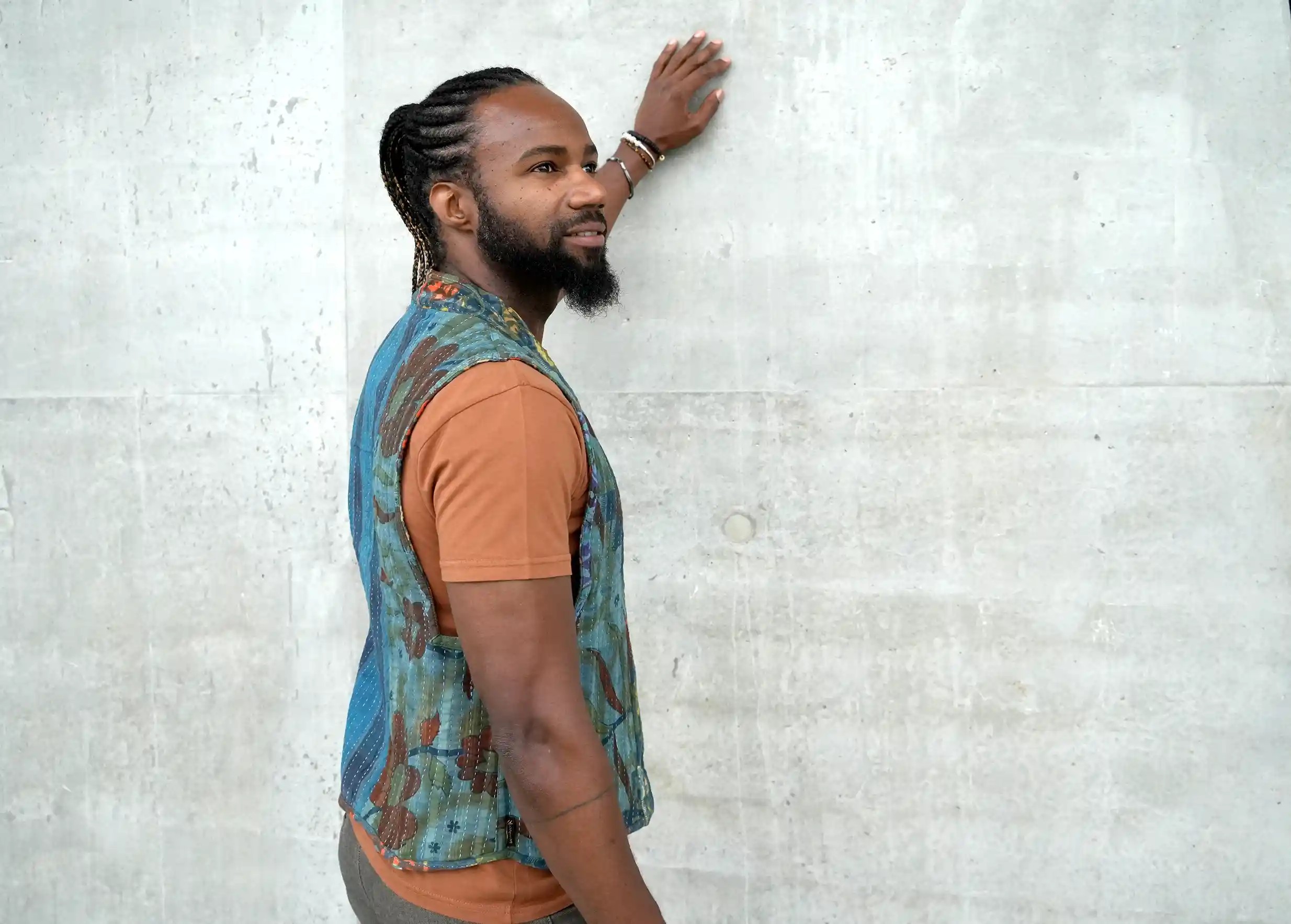 Homme de dos posant sa main contre un mur, portant un boléro gilet réversible en coton kanta matelassé
