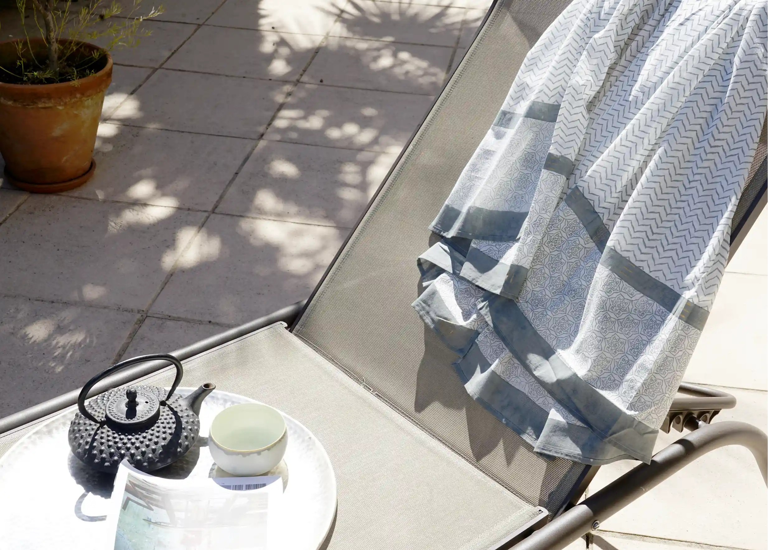 Zigblock pareo, Chinese blue colour, draped over an outdoor deckchair, with a carafe and books placed on top