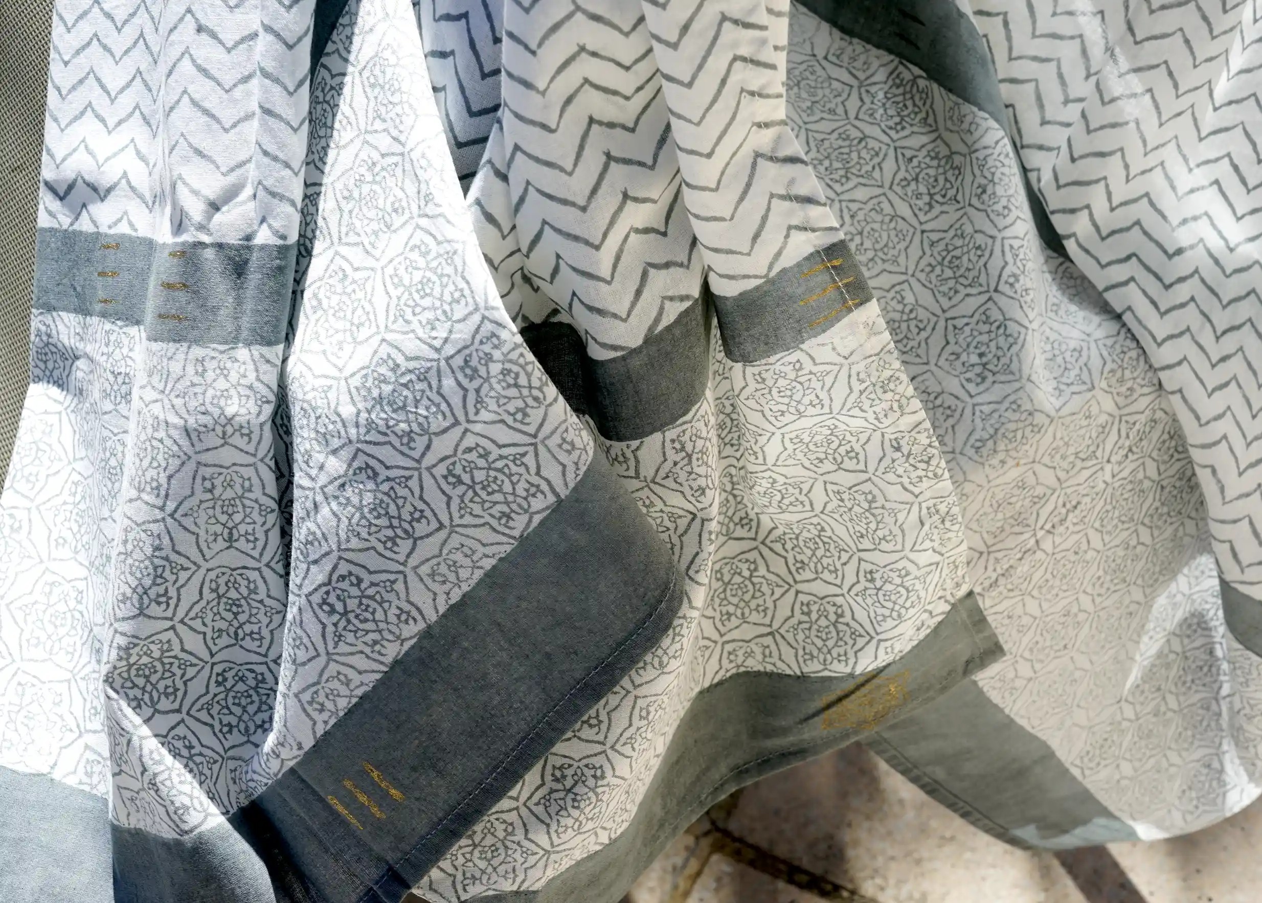 Cheche sarong with block print draped over an outdoor chair, sunny setting