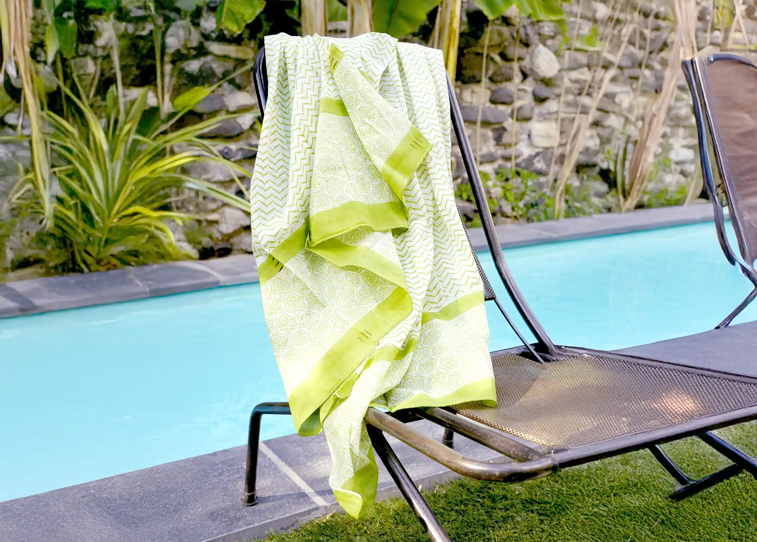 Zigblock pareo-chèche with wide green stripes and blockprint motifs on a chair near a swimming pool