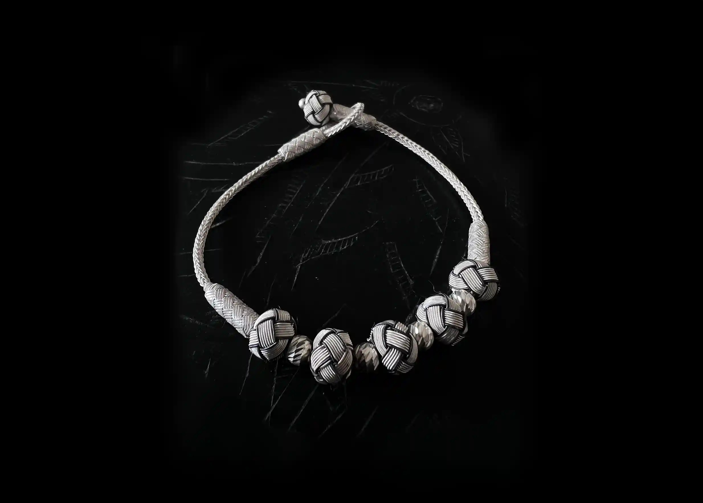 Silver bracelet with 5 white knots, by Karawan, photo on black background