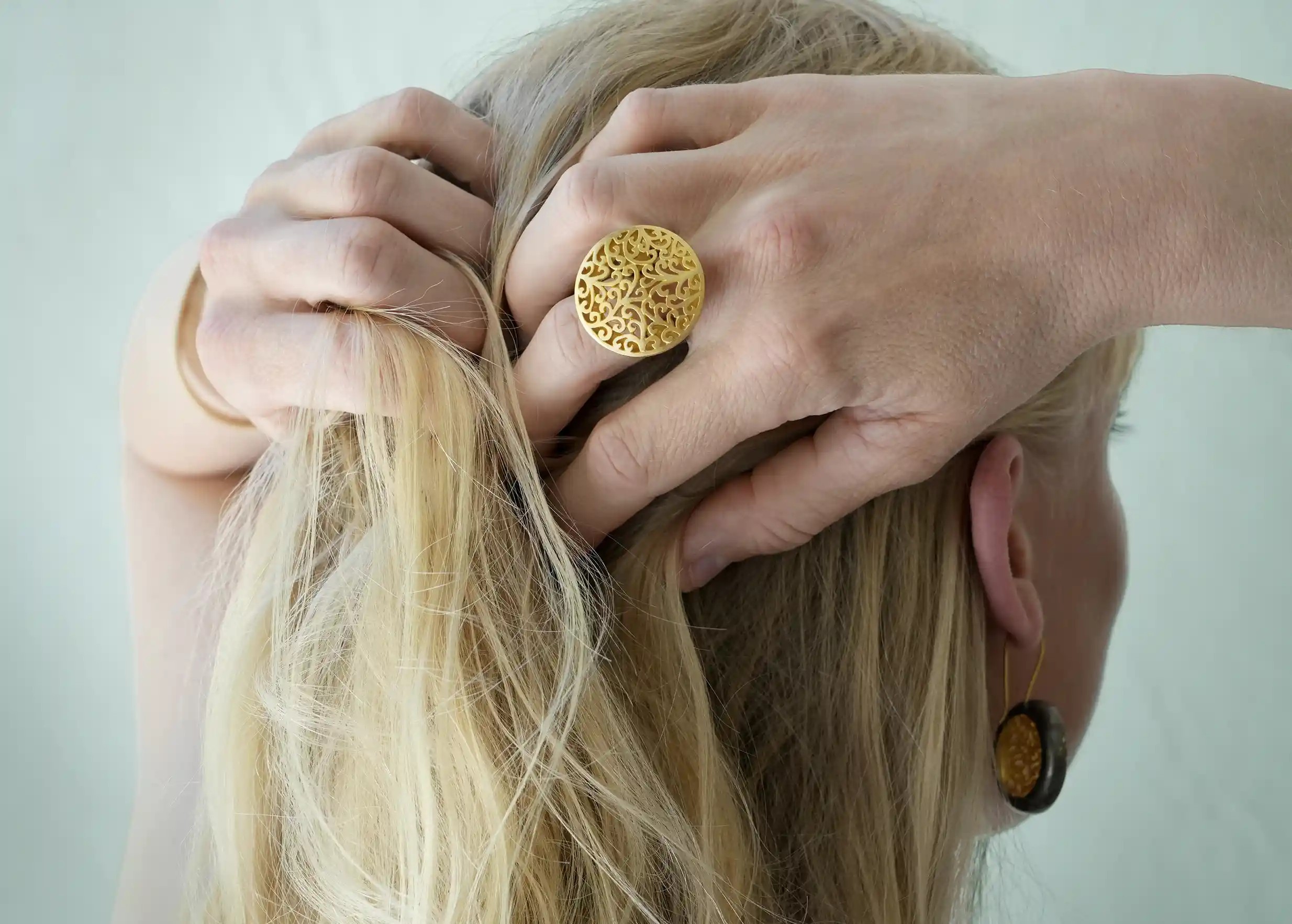 Femme de dos portant une bague de la collection Jardin Secret en laiton au design ajouré