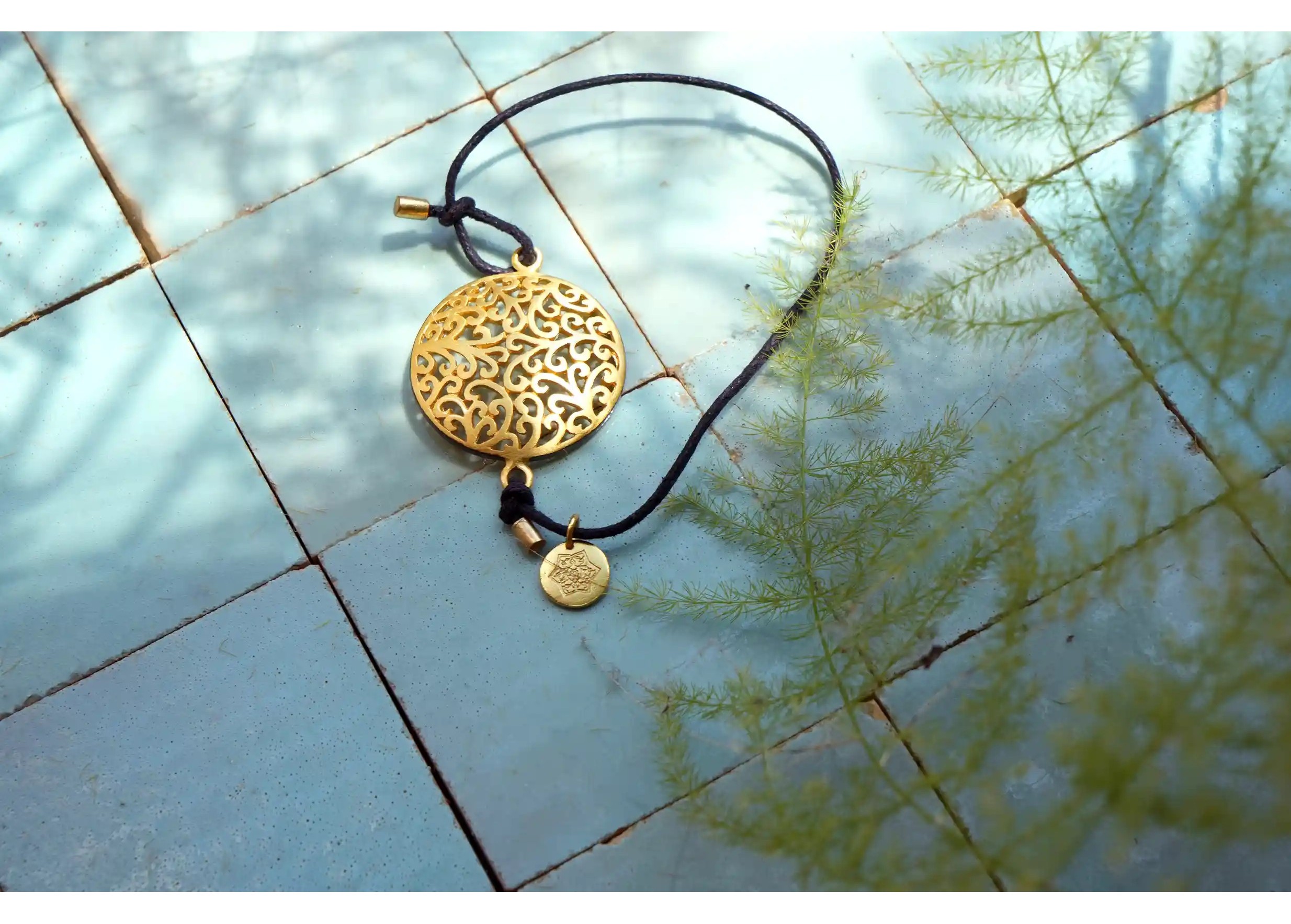 Gilded-plated brass bracelet Secret Garden seen from above on a tiled surface