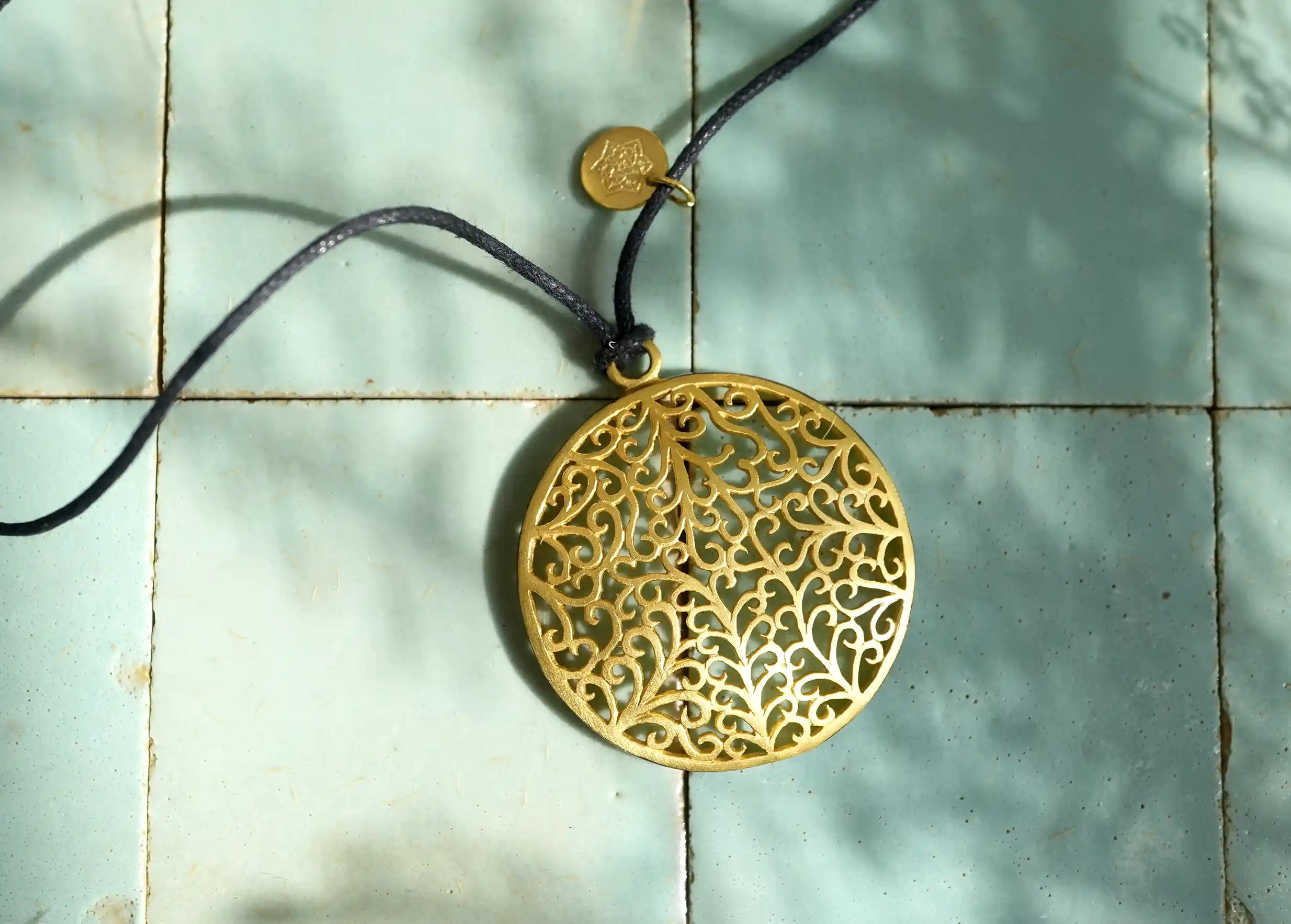 Focus on the gilded-plated brass pendant from the Secret Garden range with black cord