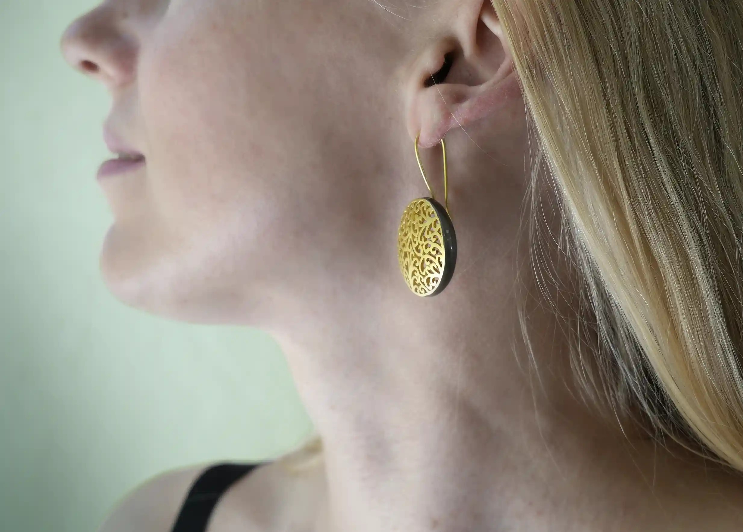 Femme portant les boucles d'oreilles en laiton doré de la collection Jardin secret par Karawan