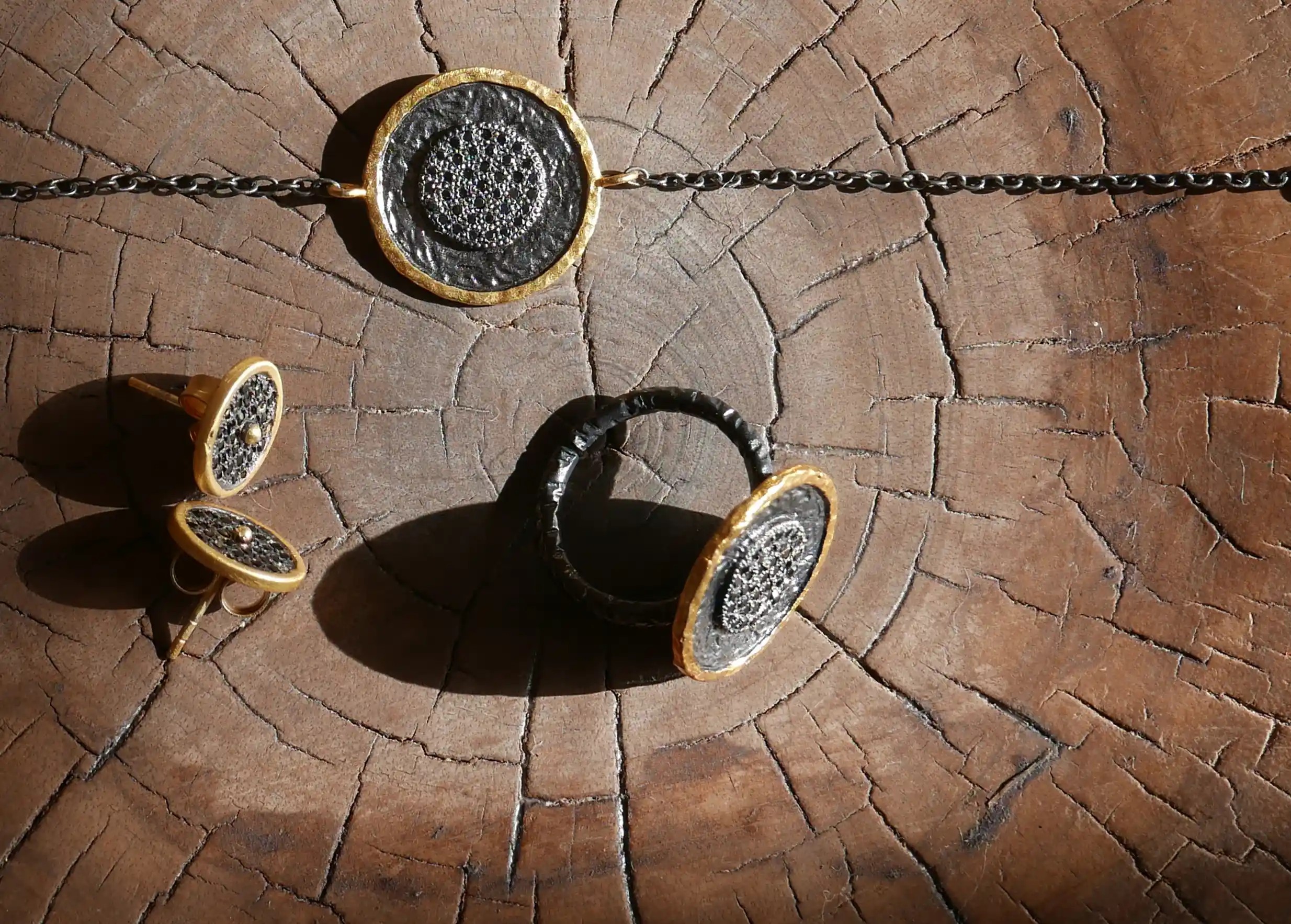 Collection de bijoux en laiton comprenant des bracelets, bagues et boucles d'oreilles, présentés sur un support en bois