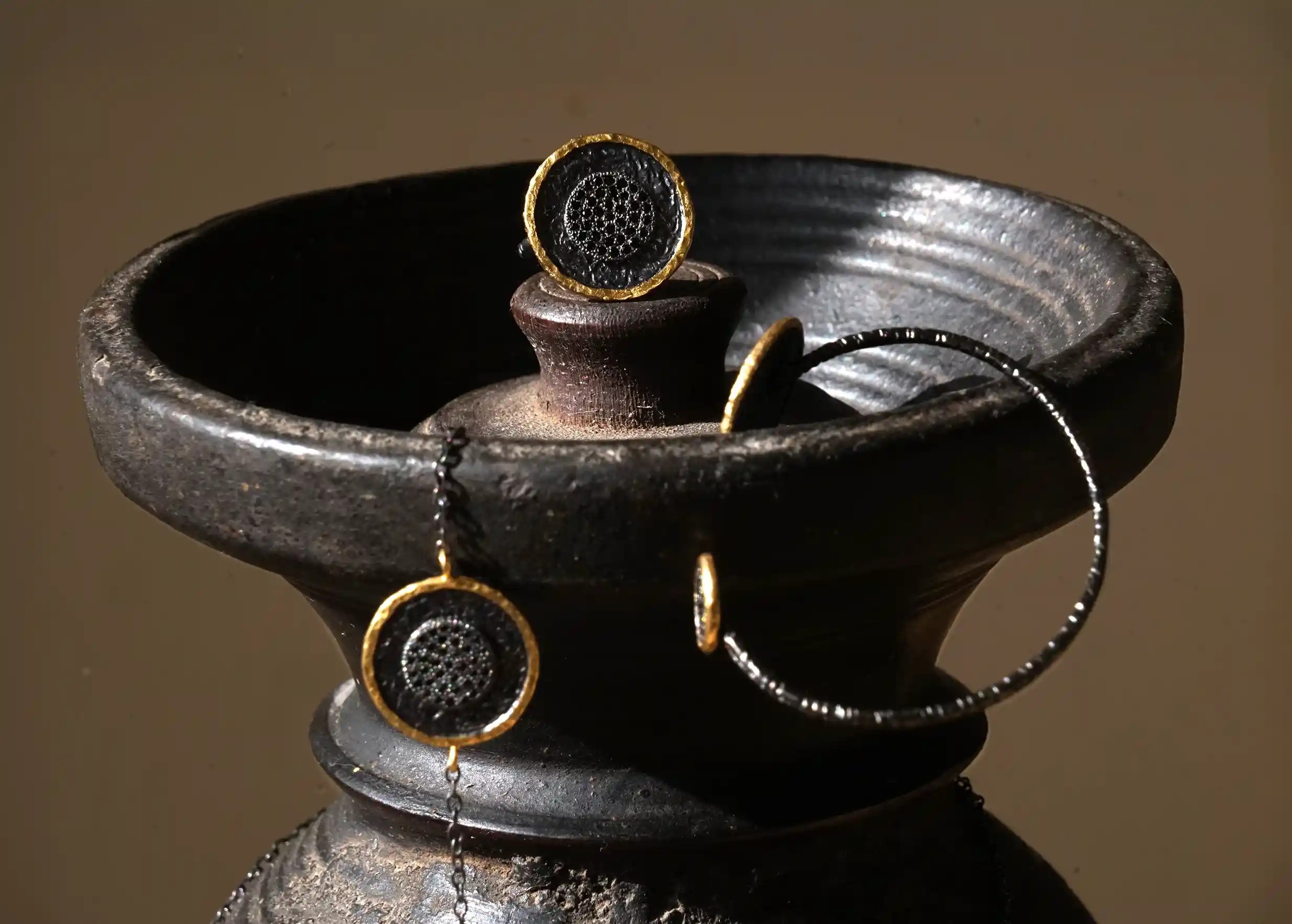 Brass ring from the Nuit des Temps collection displayed on top of a vase with other Karawan jewellery