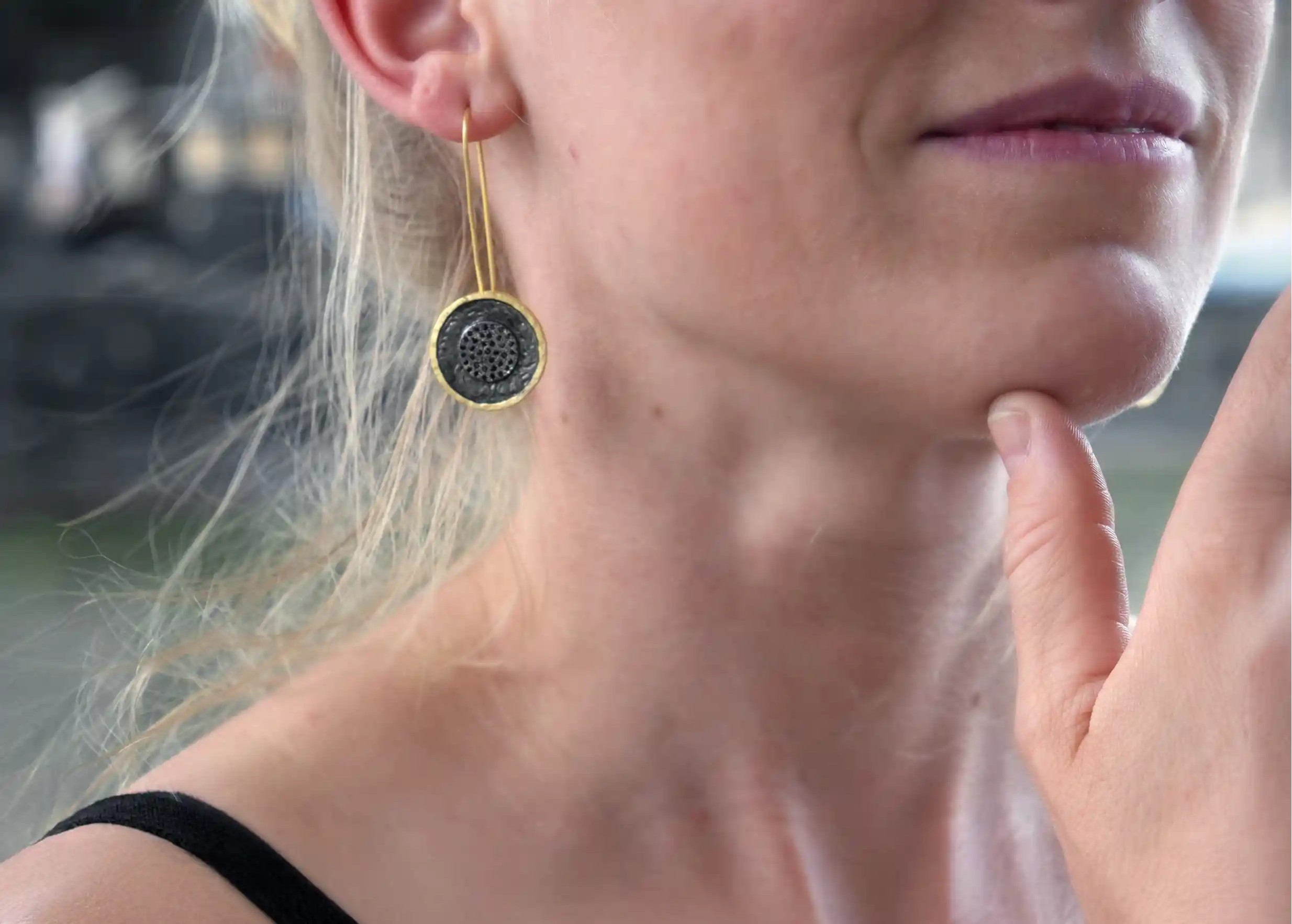 Boucle d'oreille en laiton et zirconium de la collection Nuit des Temps portée à l'oreille d'une femme