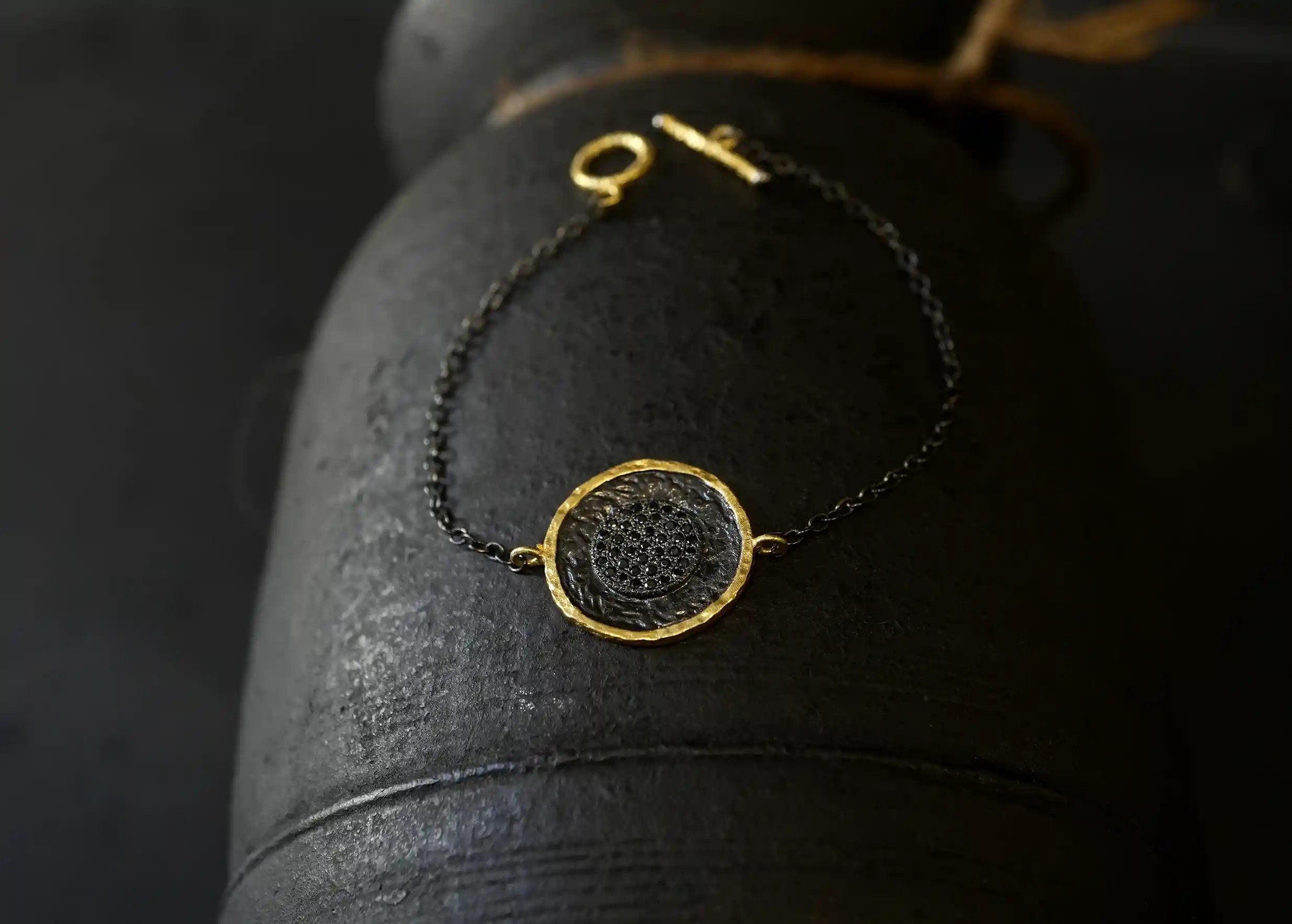Brass bracelet from the Nuit des Temps collection hanging on the side of a vase