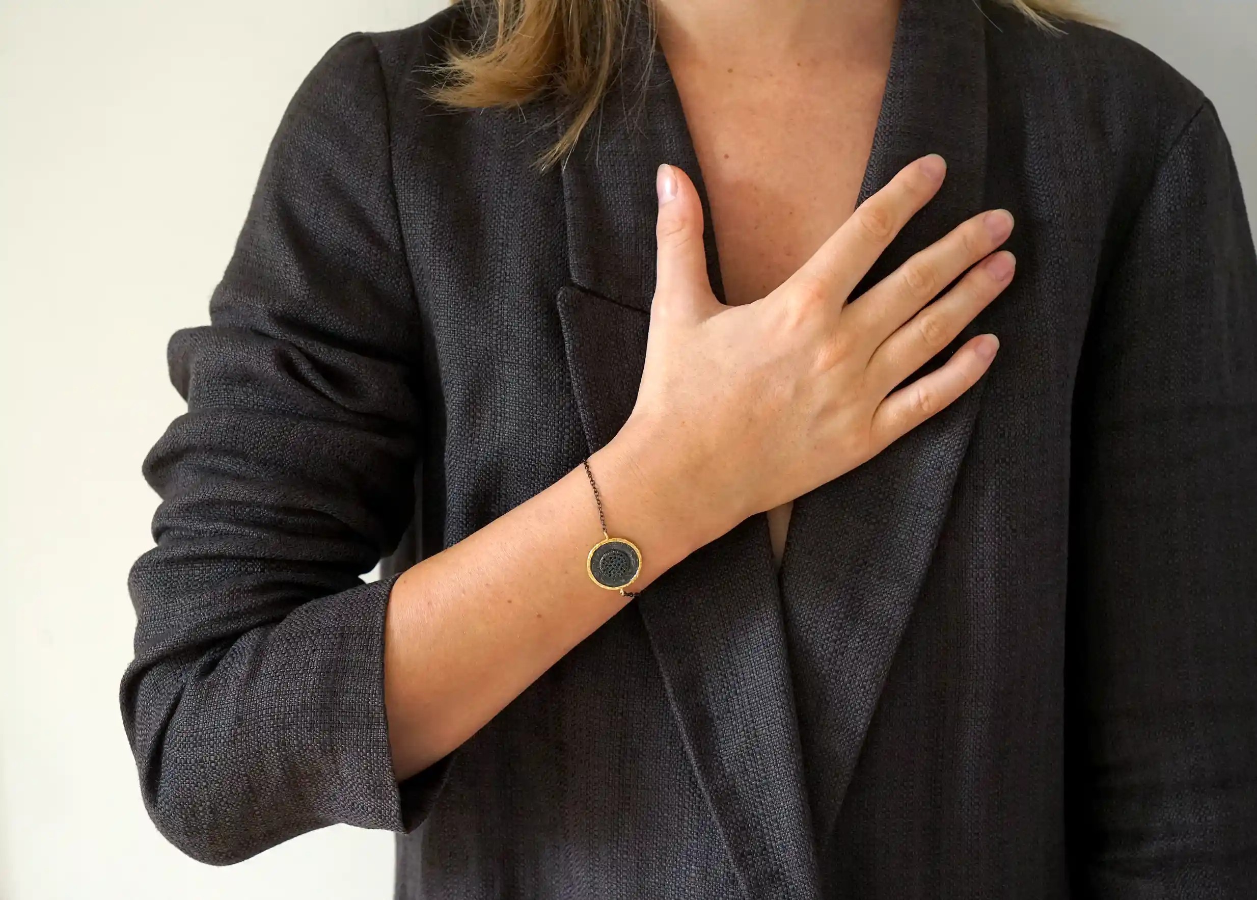 Woman wearing a brass bracelet from the Nuit des Temps collection around her wrist