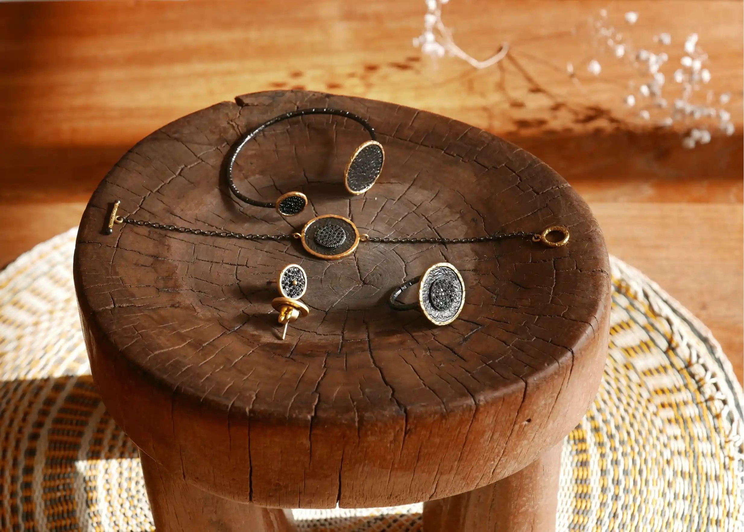 Collection de bijoux en laiton comprenant des bracelets, bagues et boucles d'oreilles, présentés sur un support en bois